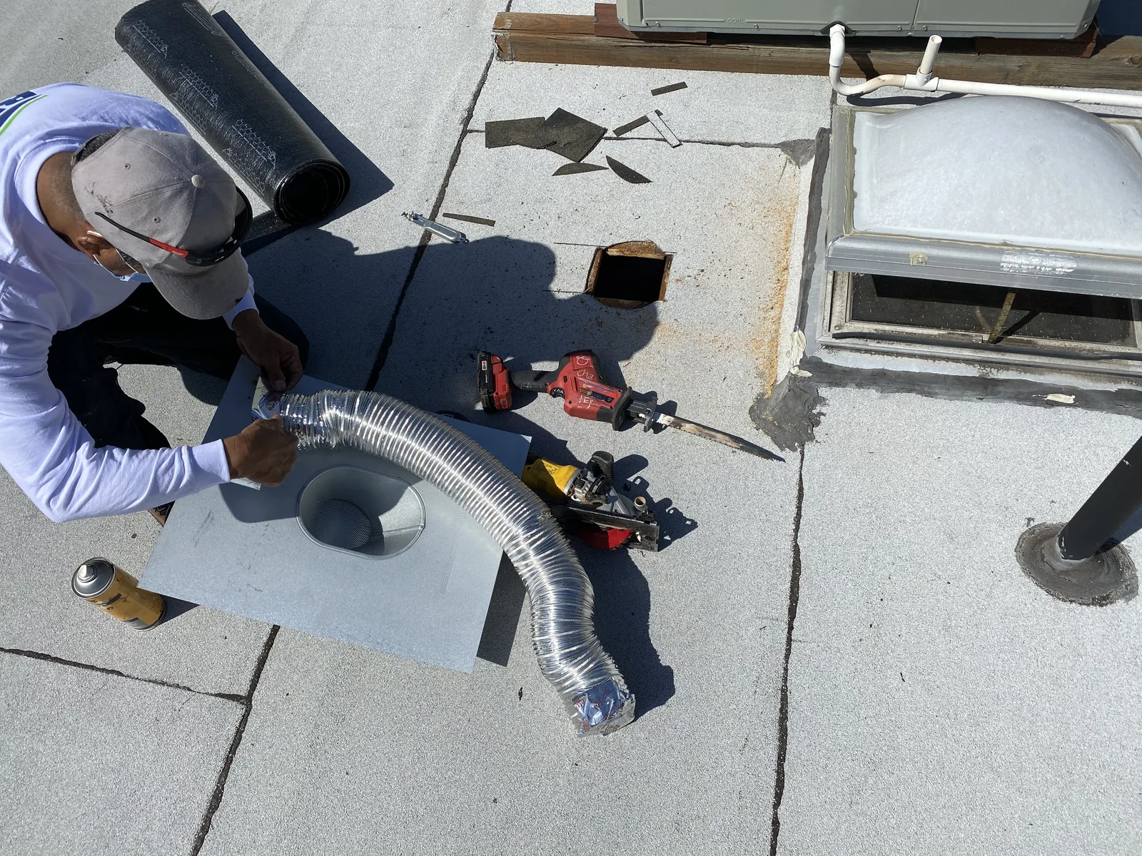 The new flat roof with a skylight and vent penetration being installed