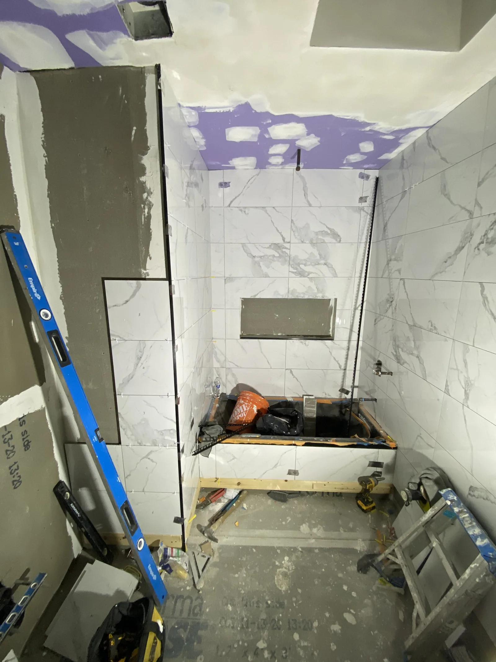 Tile installed on shower walls with the niche formed and a level checking plumb