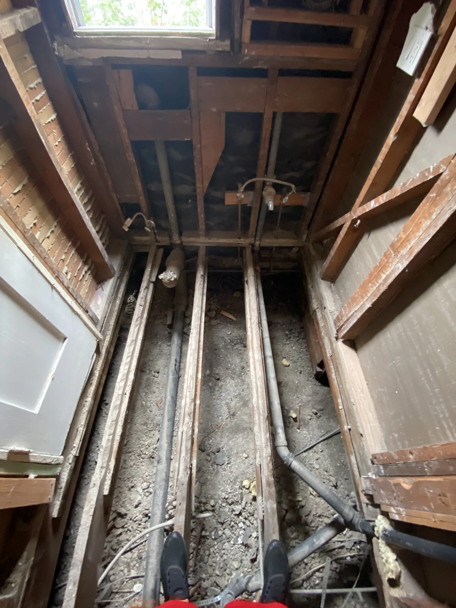 A worker standing in a raised crawlspace beneath a bathroom during the repipe
