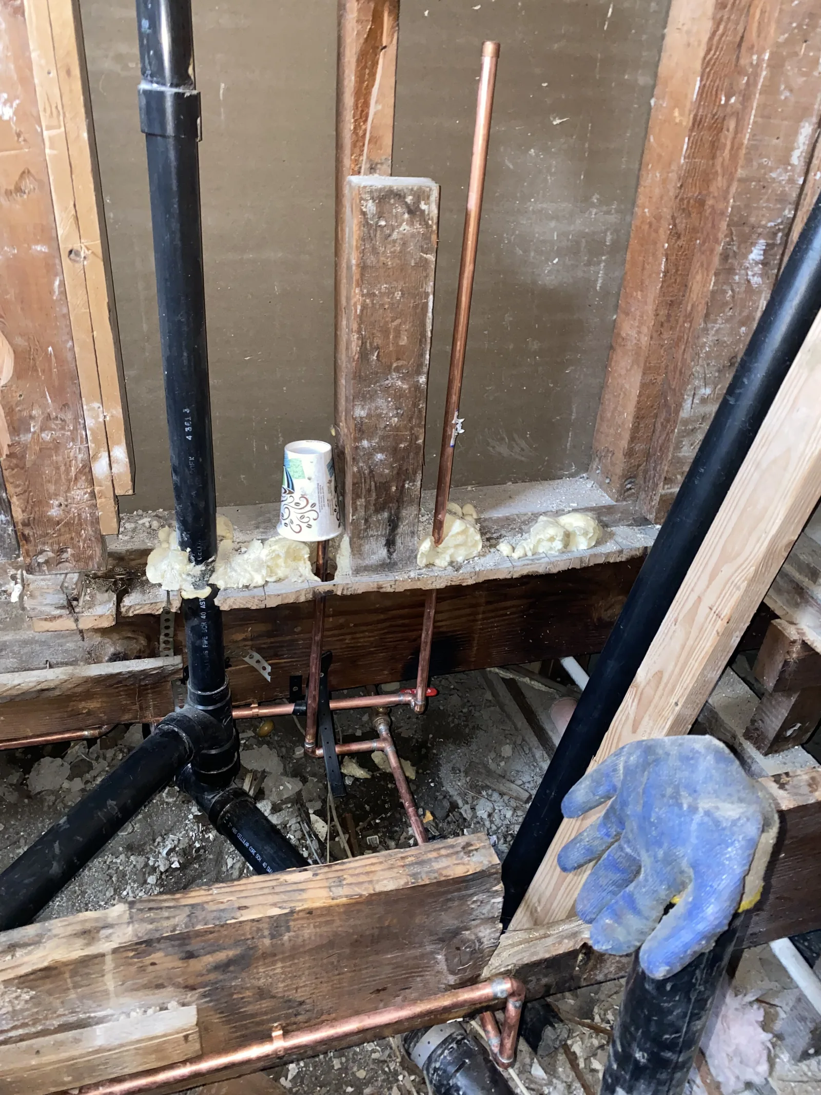 New copper supply lines run beneath the house next to a section of rotted framing