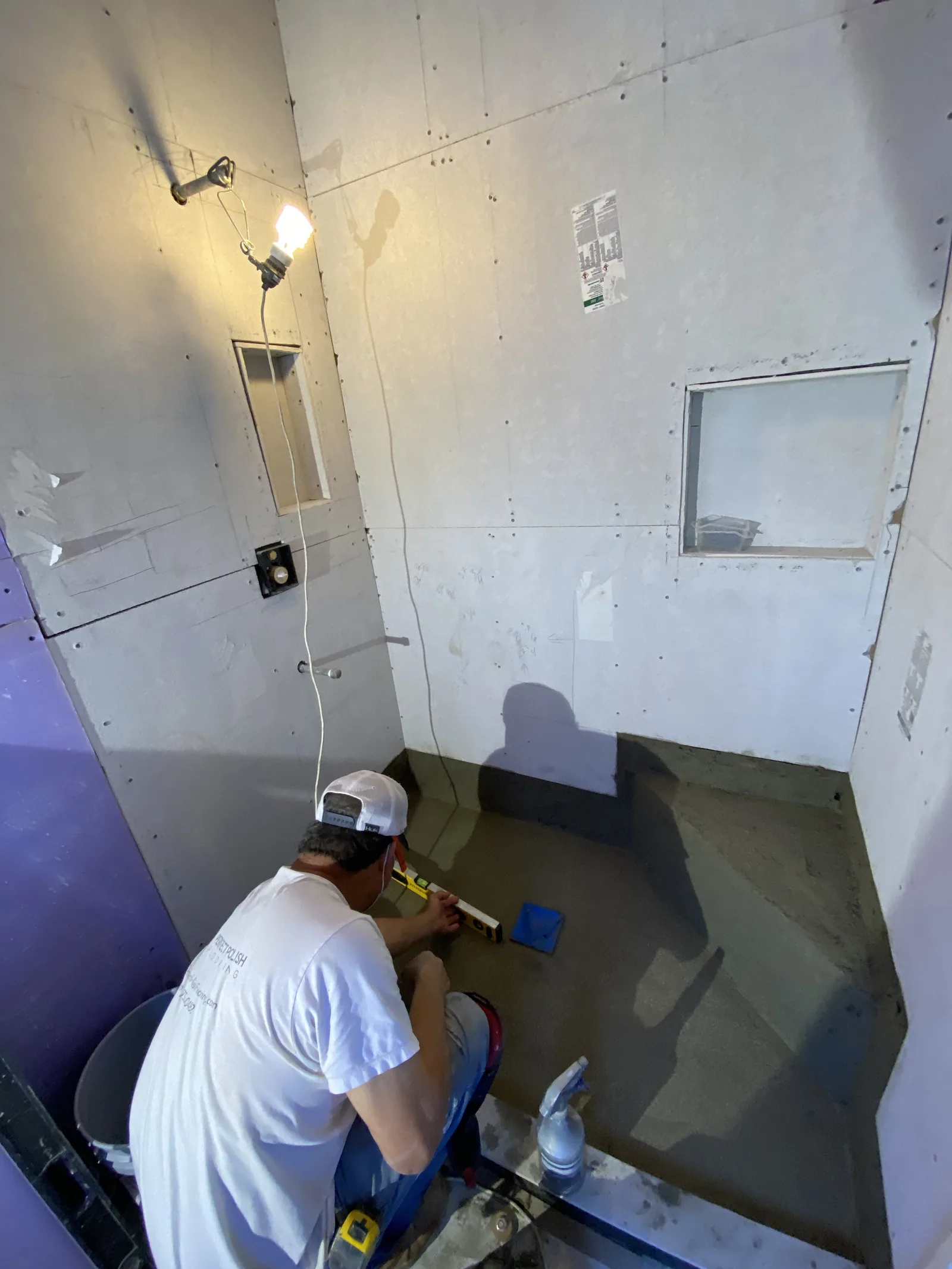 A worker leveling a mortar bed for a new shower floor before tile