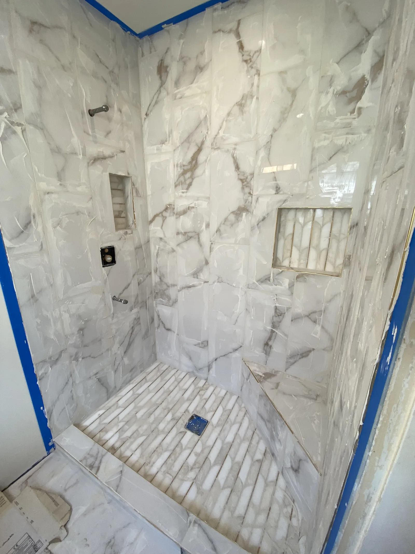 Freshly grouted tile in a shower, still covered in protective film