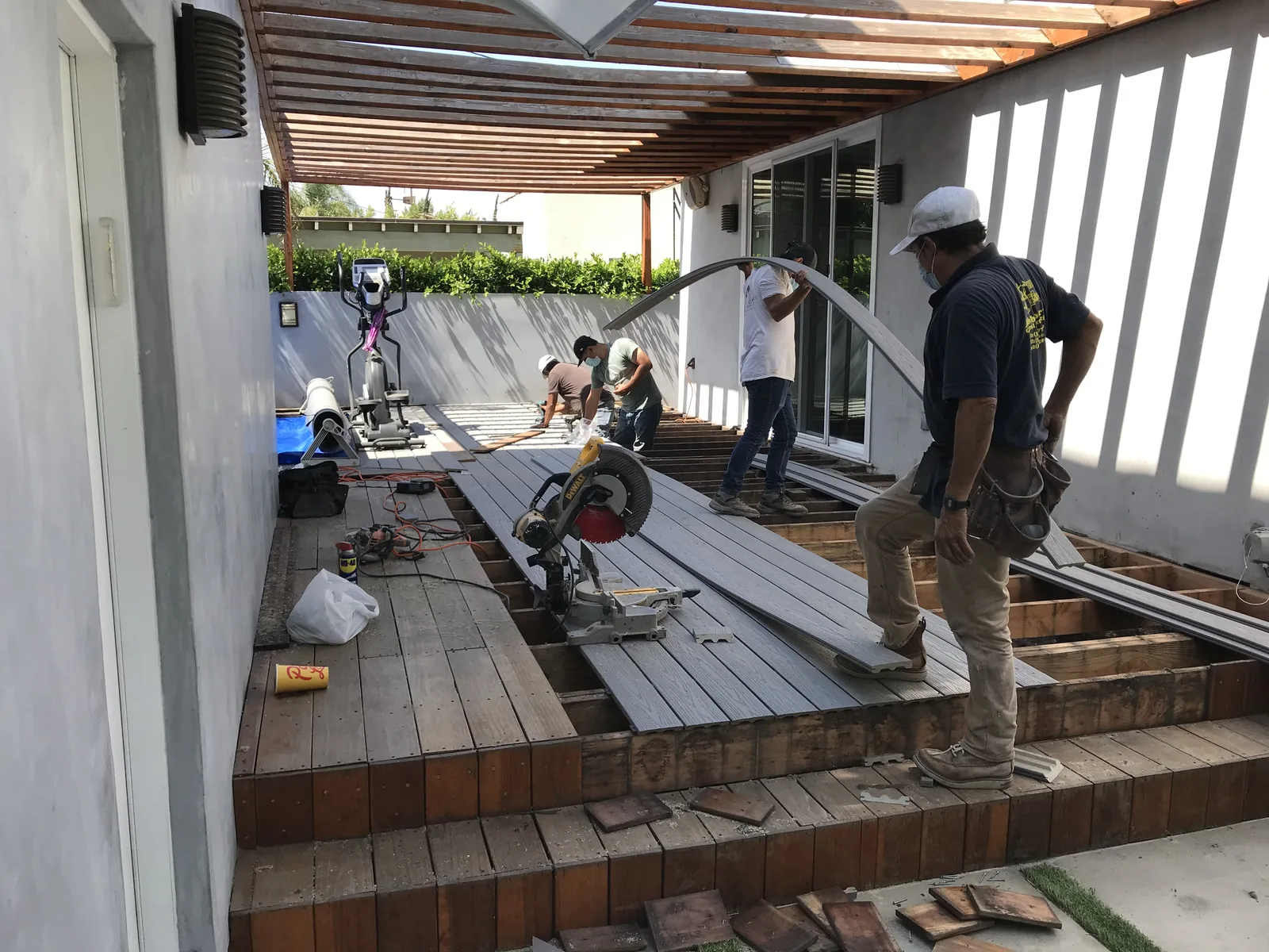 Workers cutting and installing new Trex decking under the pergola