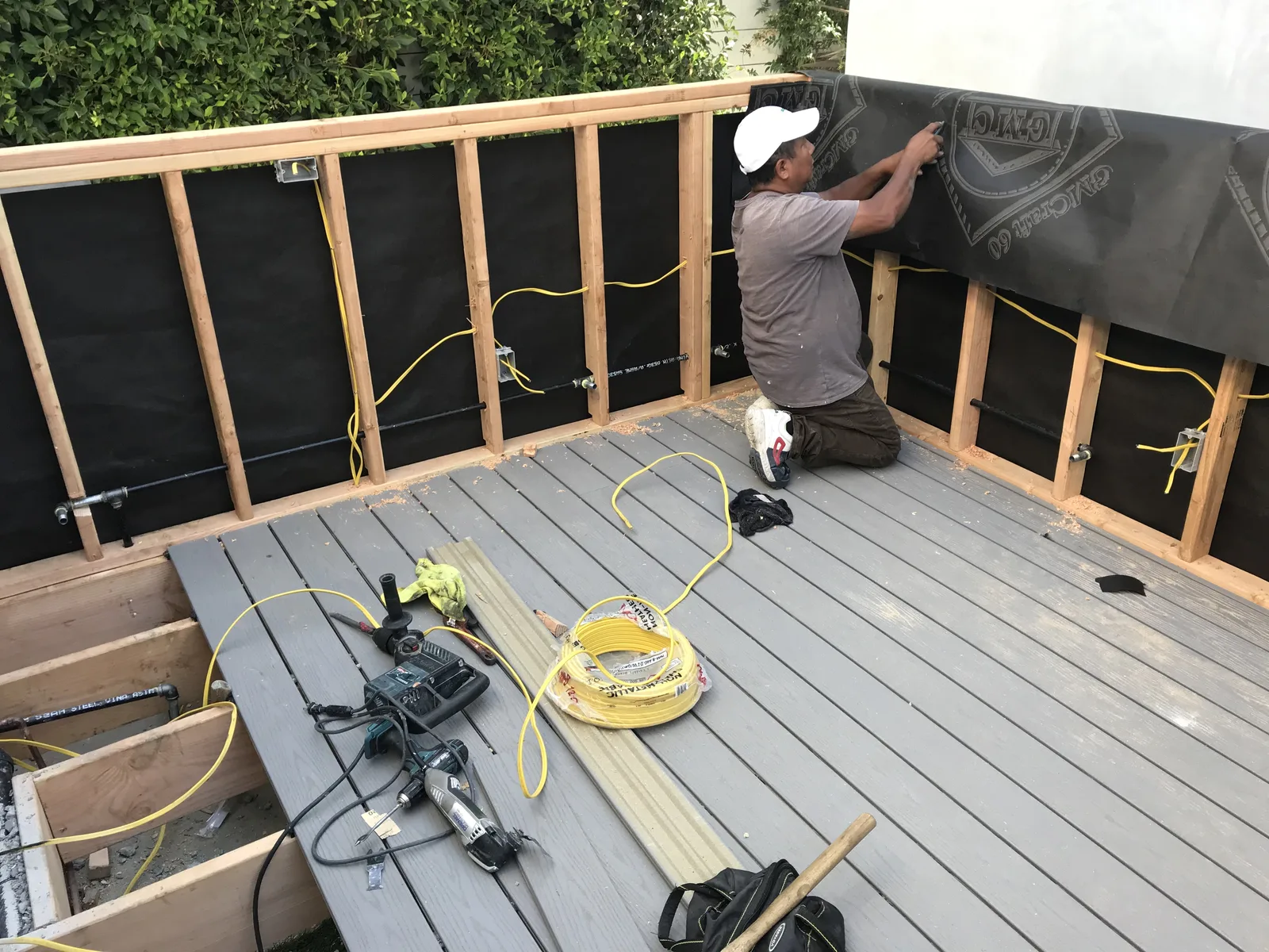 Wall framing and weather barrier on a deck extension, with new decking down