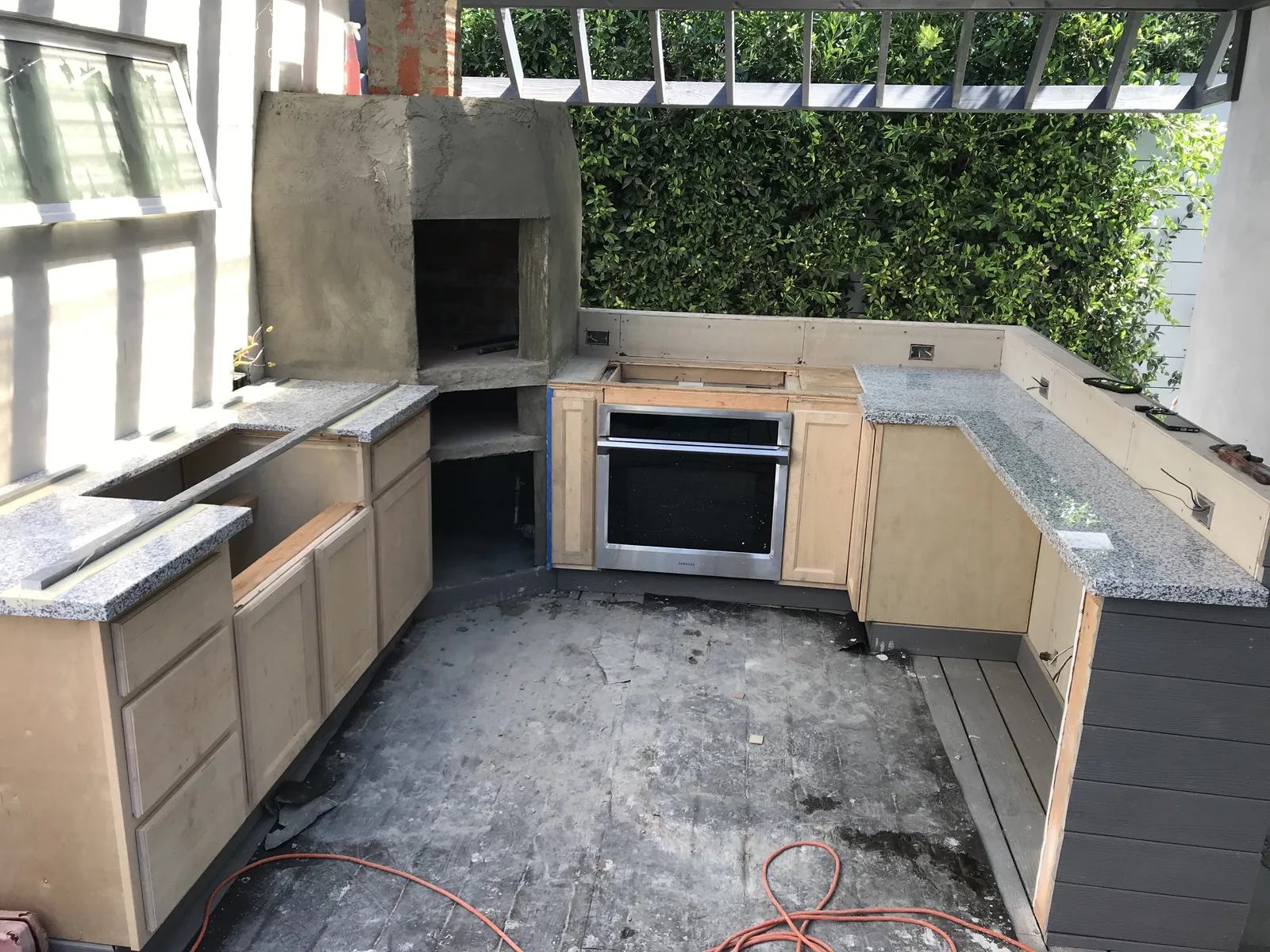 A kitchen structure with stone countertops installed and an oven chimney taking shape