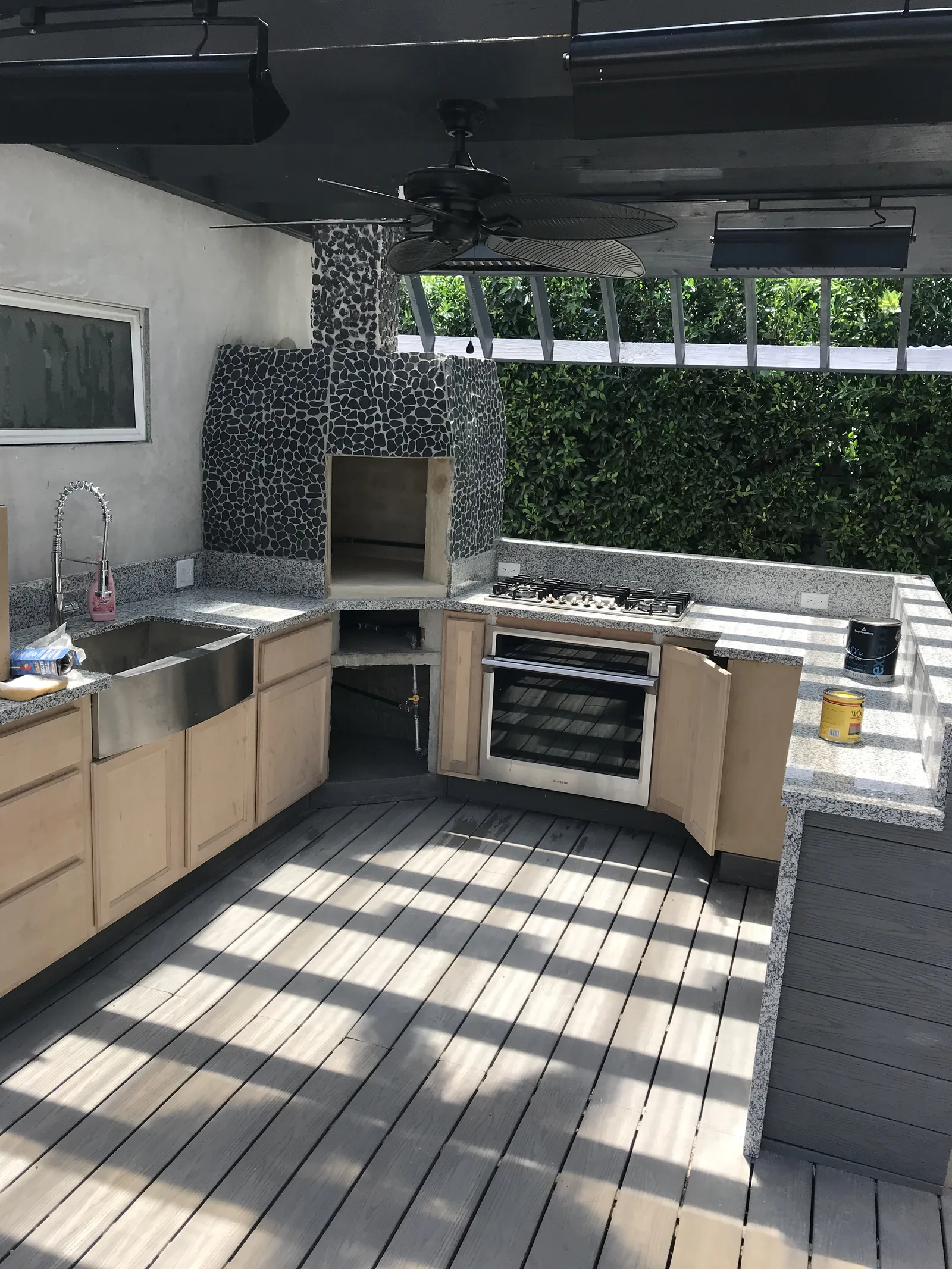 A kitchen with sink, range, and complete river rock facing, cabinets not yet stained