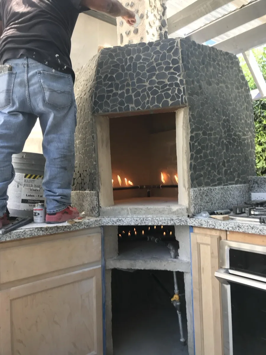 A close view of a lit oven with a worker nearby, cabinets not yet stained