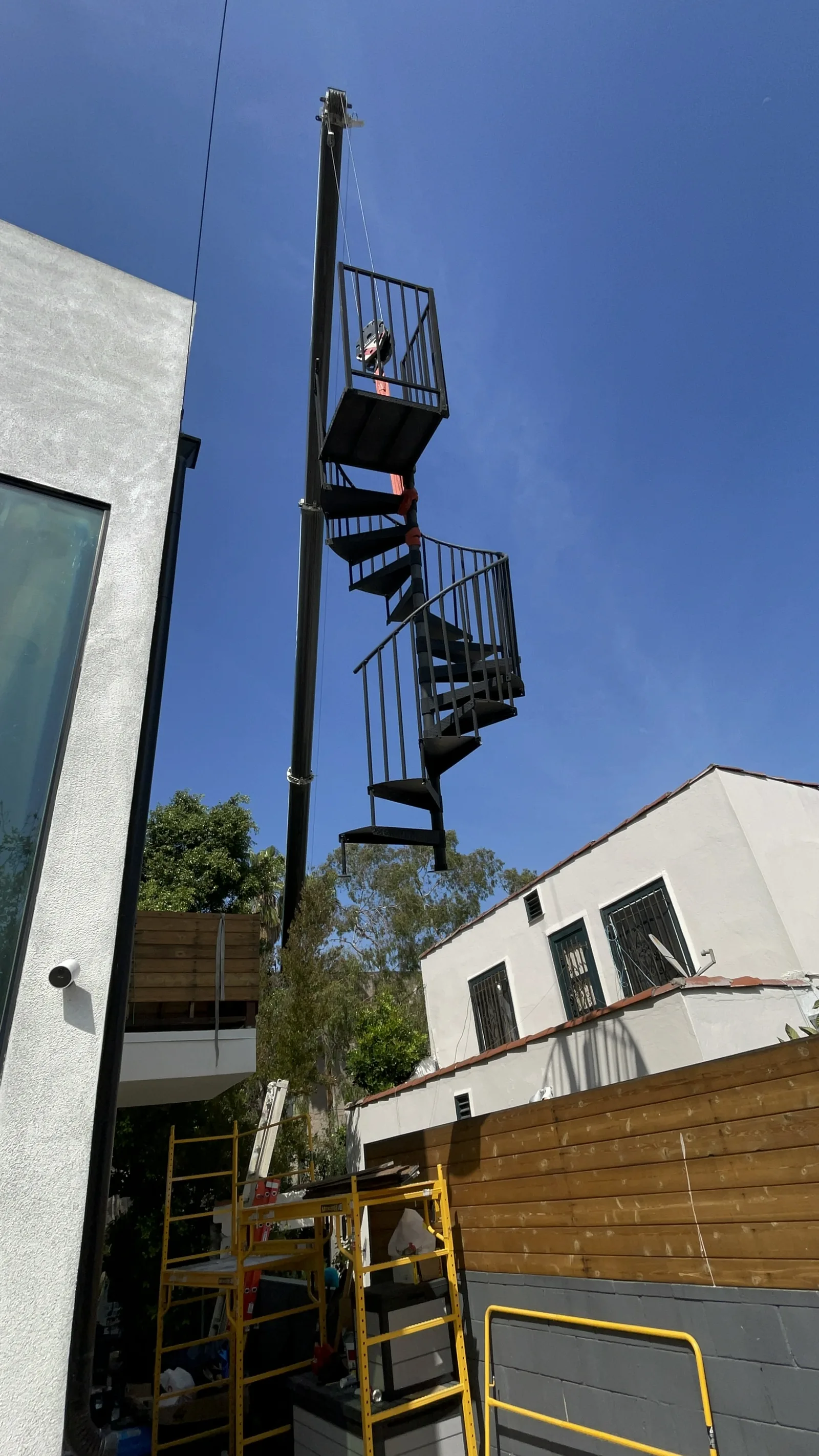 A mobile crane lifting the original spiral staircase away from the building