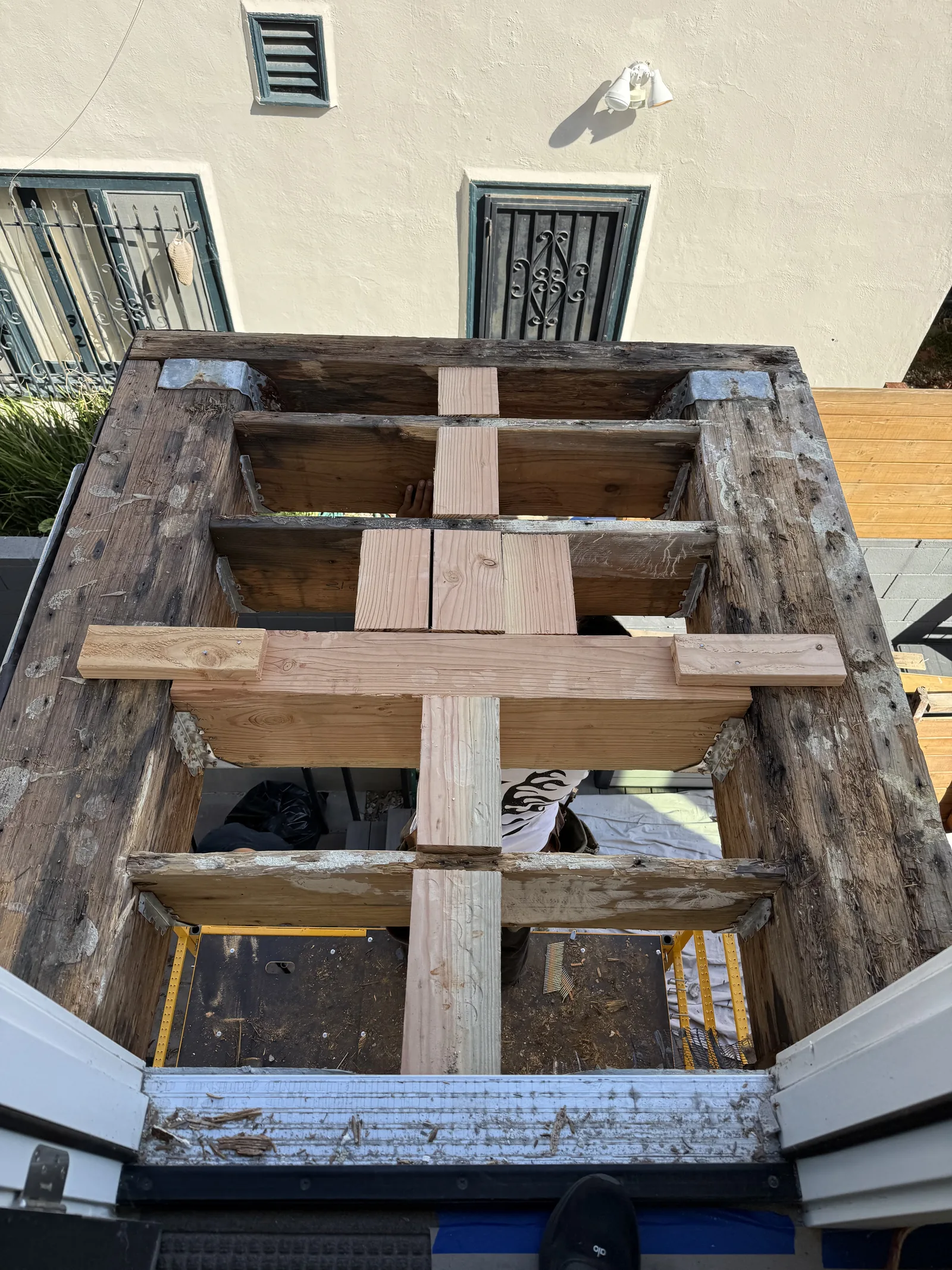 An overhead view of the balcony's framing skeleton with the old rotted joists and new cross bracing