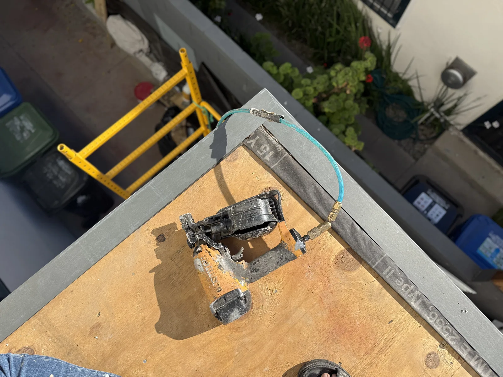 A power tool resting on the new plywood deck subfloor with a grounding wire clipped to the edge flashing
