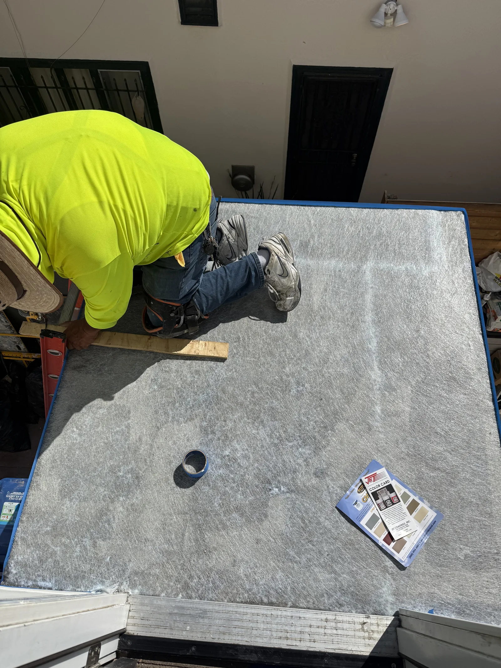 A worker applying the spray-on fiberglass waterproof coating to the deck surface