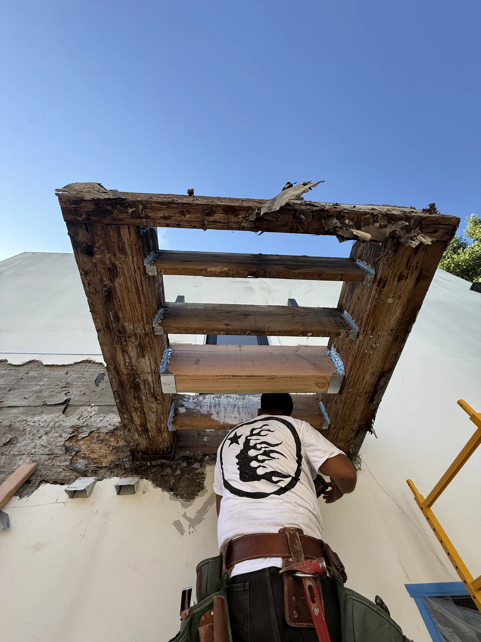 Rotted balcony framing exposed after demolition, seen from below