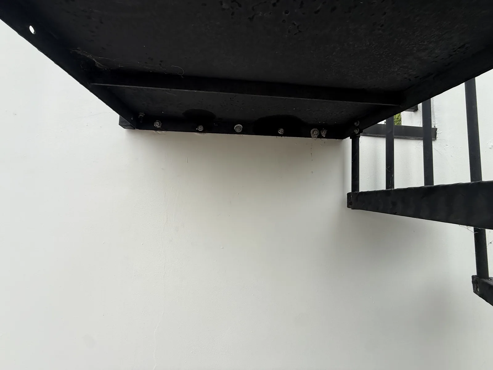 The finished underside of the rebuilt balcony, painted black, with the staircase visible alongside