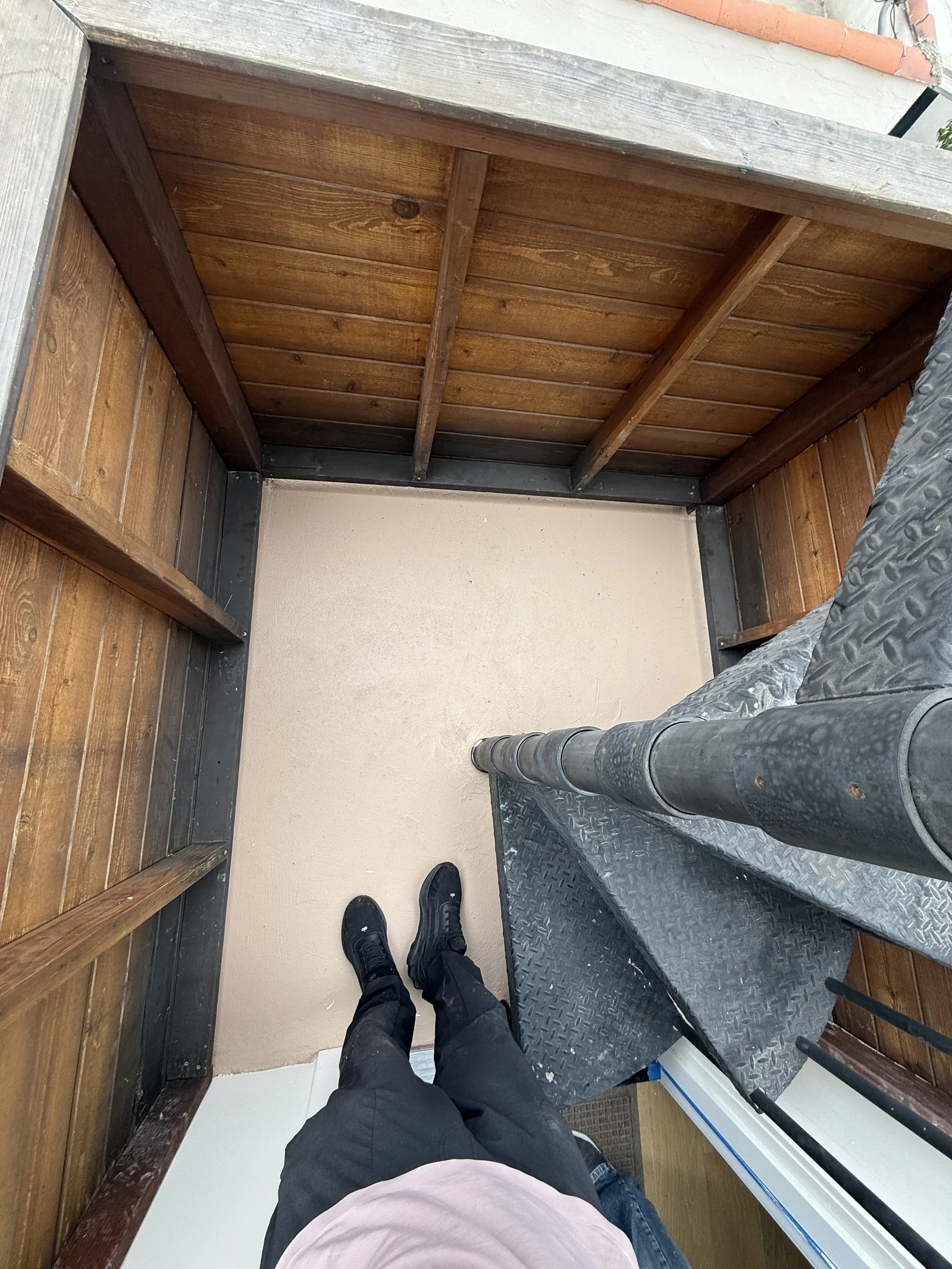 A view looking down a finished interior stairwell with a wood plank ceiling