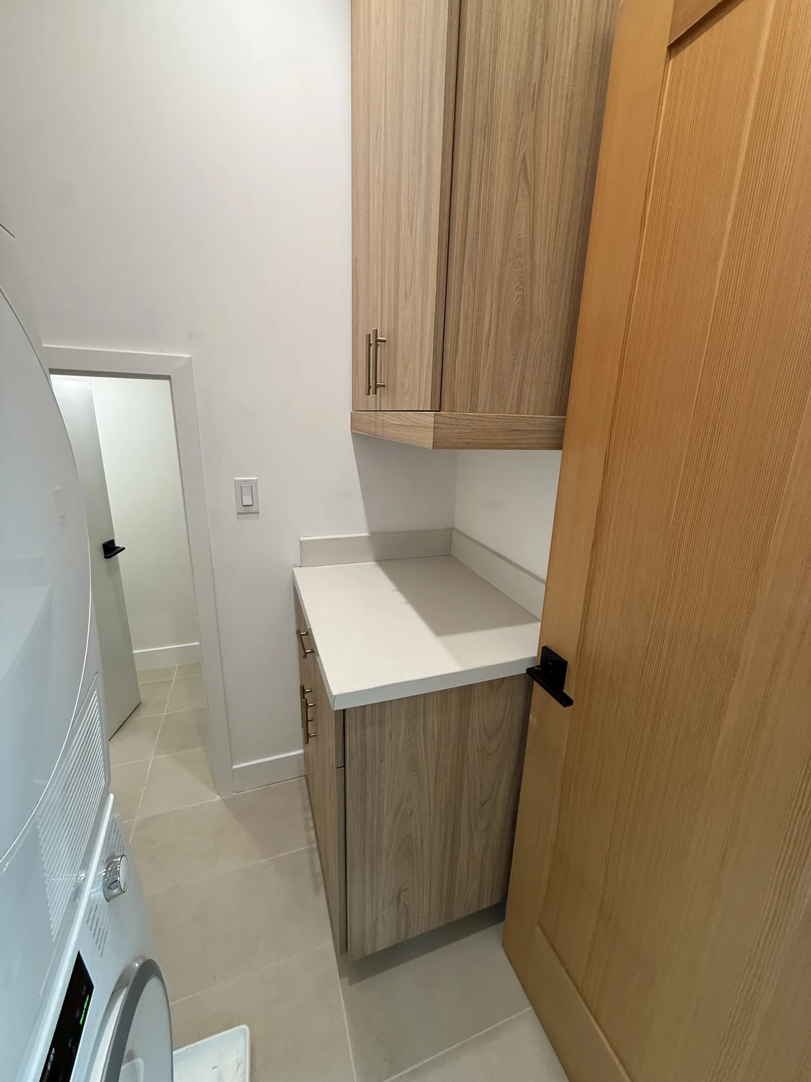 A finished kitchenette or laundry nook with white cabinets and a quartz counter