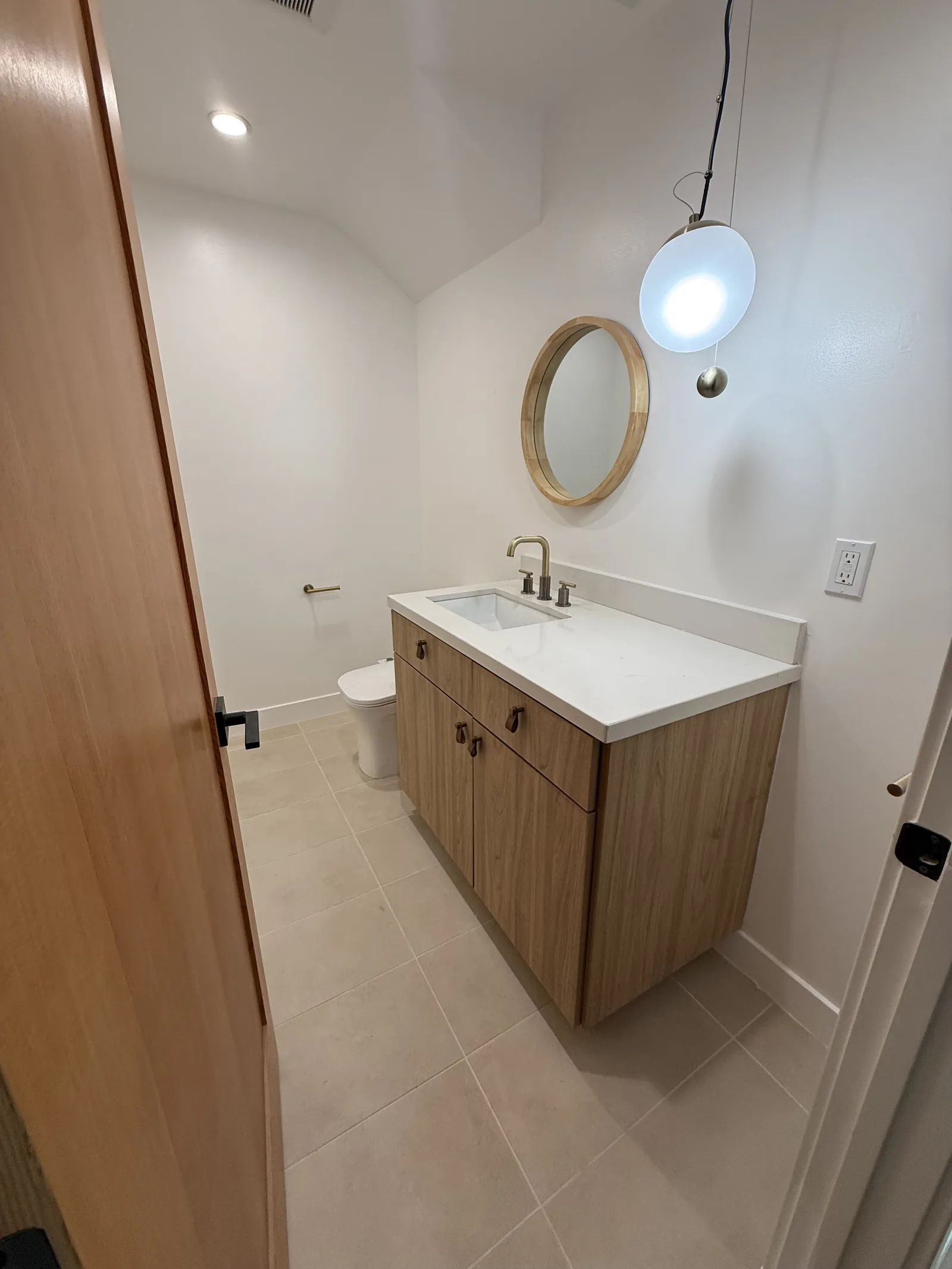 A finished bathroom with a wall-hung vanity, tile floor, and pendant lighting