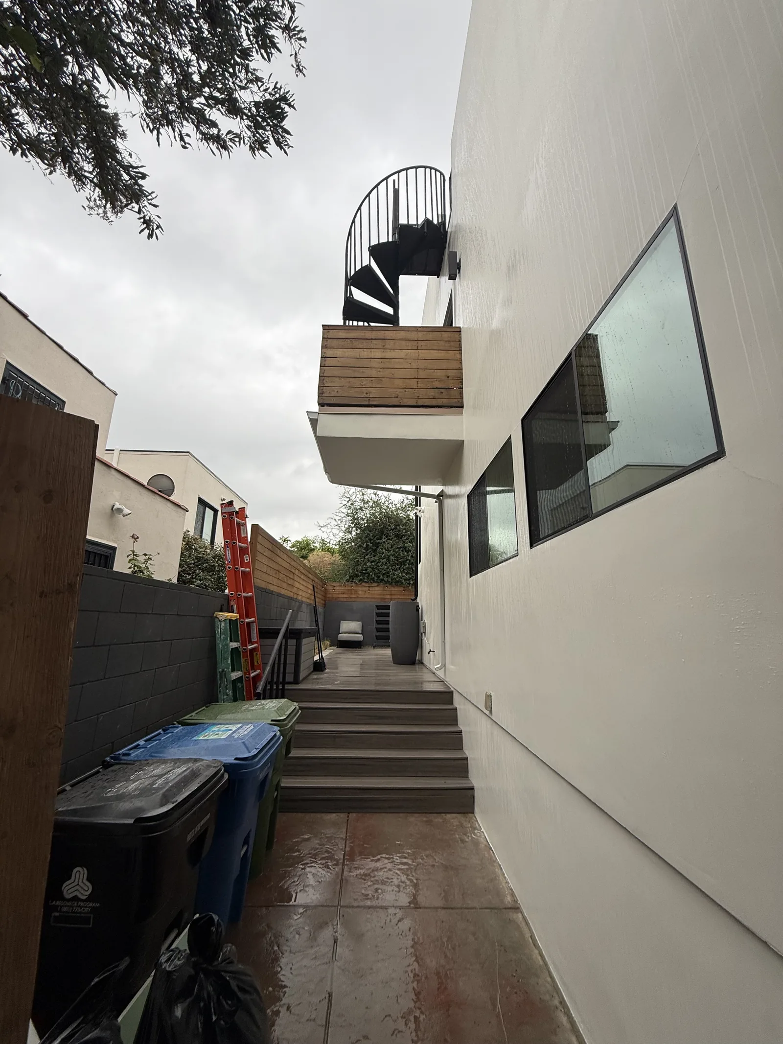 The finished balcony and staircase seen from the side walkway, with the new gutter and wood cladding complete