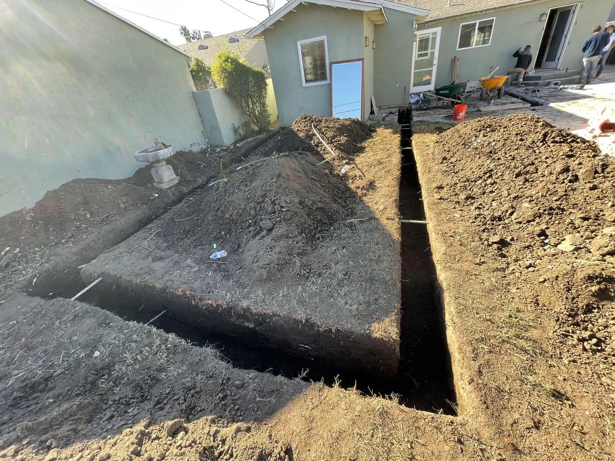 A foundation excavation trench continuing around a backyard