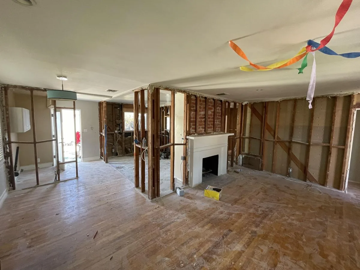 An open living room with exposed wood stud framing around a fireplace