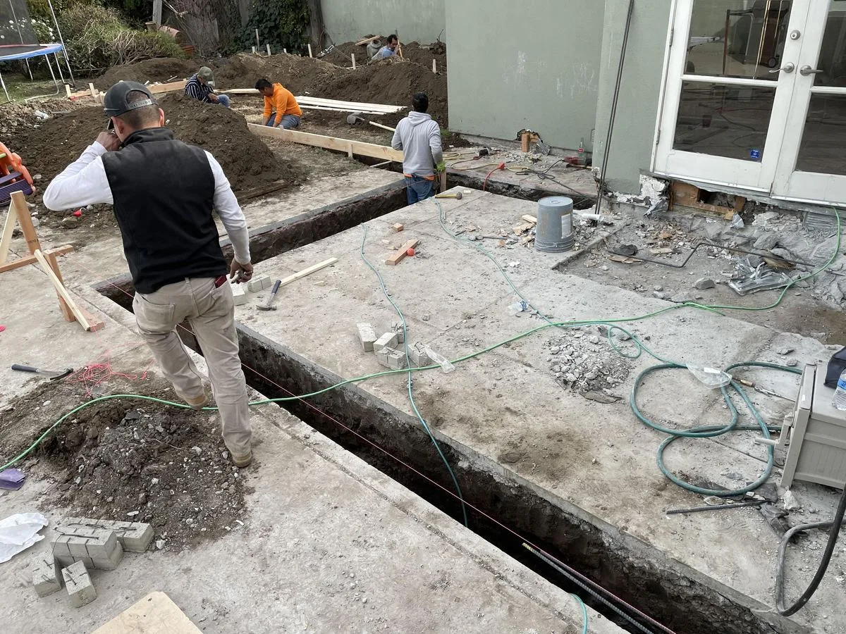 A crew member watching over a freshly poured concrete slab with rebar and forms visible