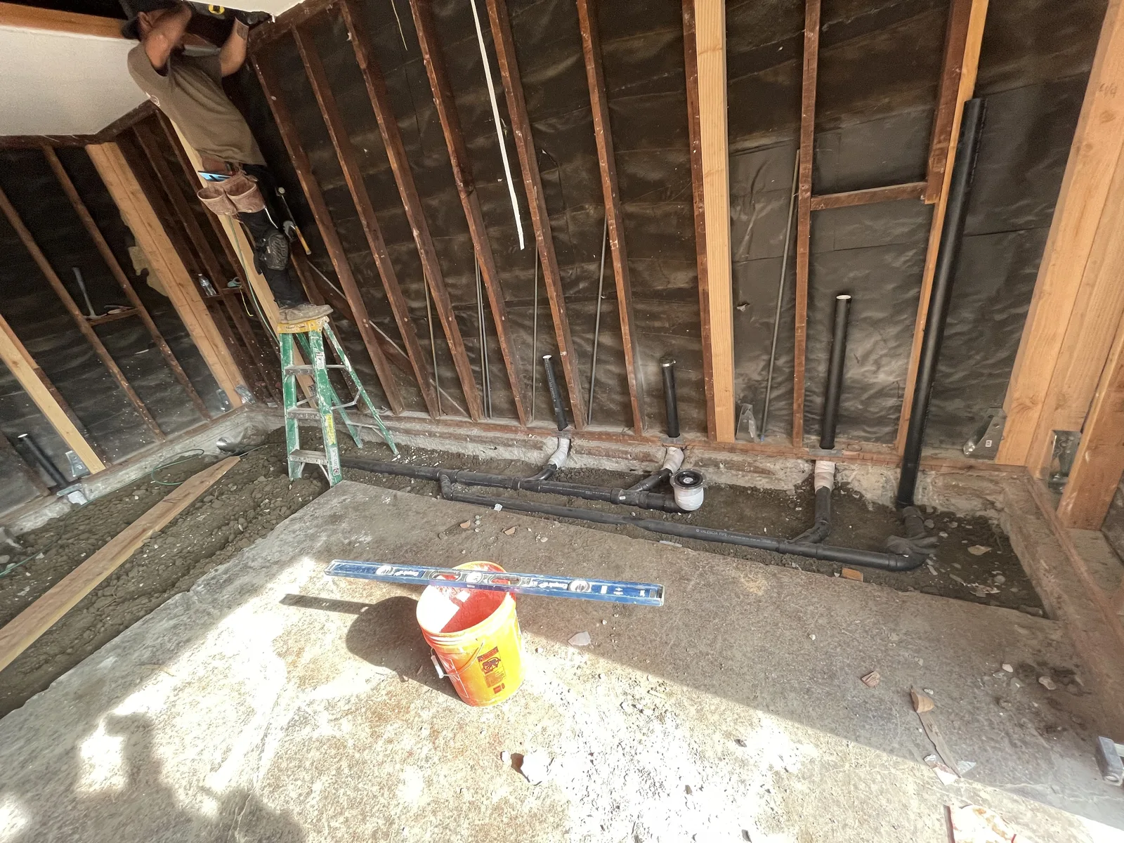 The garage interior opened to the framing, with new plumbing rough-in rising from the concrete