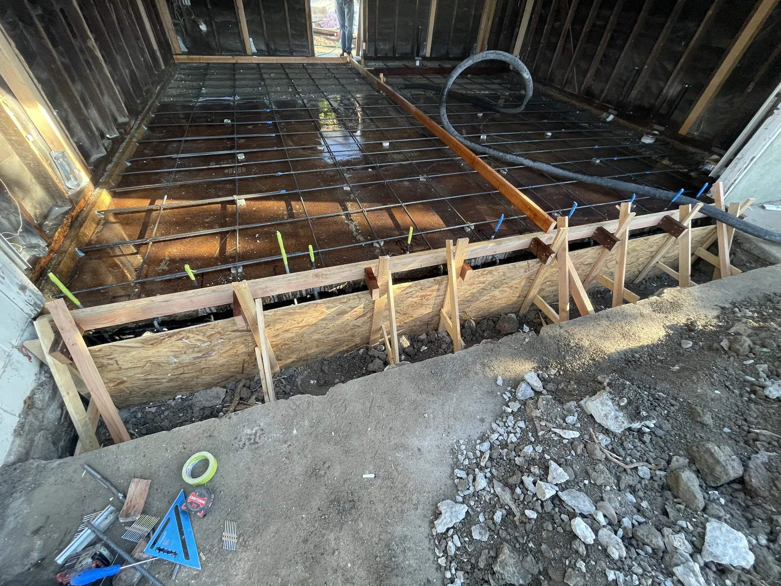 Rebar laid out for a new concrete slab, with wood forms around the edge