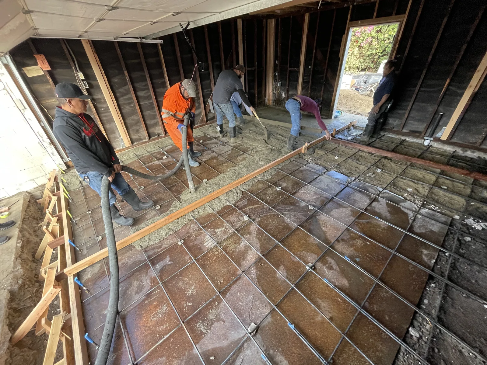 Workers pouring a new concrete slab over a rebar grid