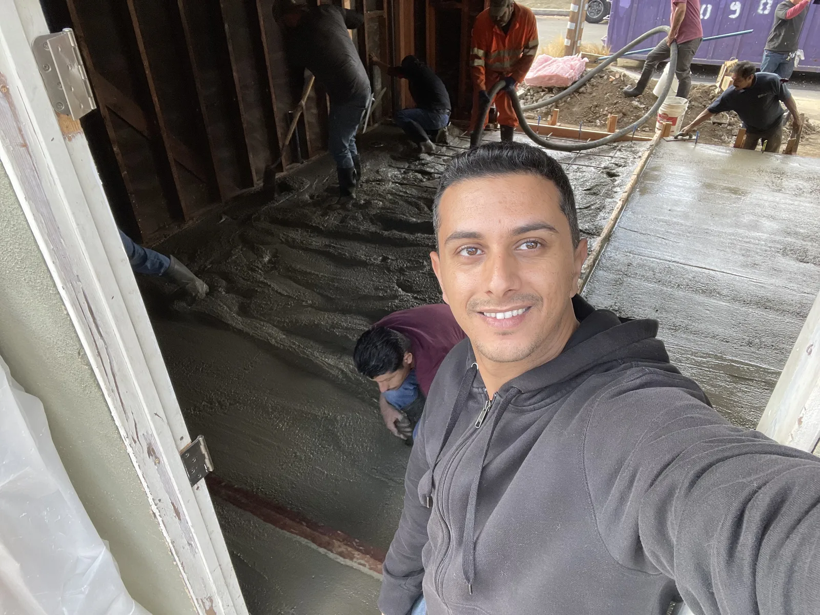 Workers pouring a concrete slab inside the garage, with the garage door opening visible at the back