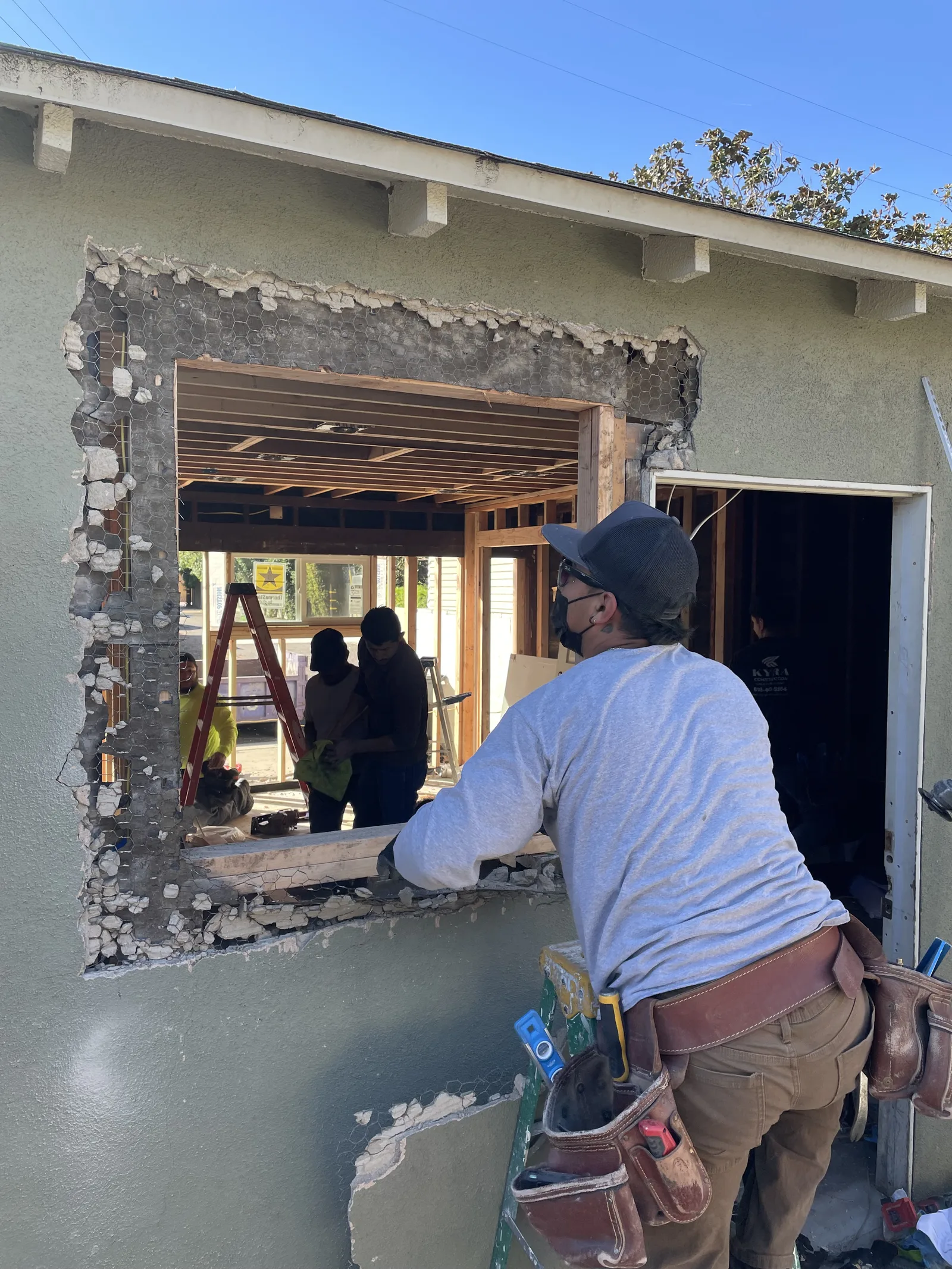 A worker cutting a new window opening into a stucco exterior wall
