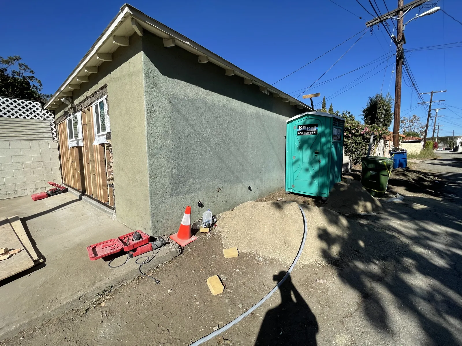 The side of a building with a new door threshold and a utility hose on the ground