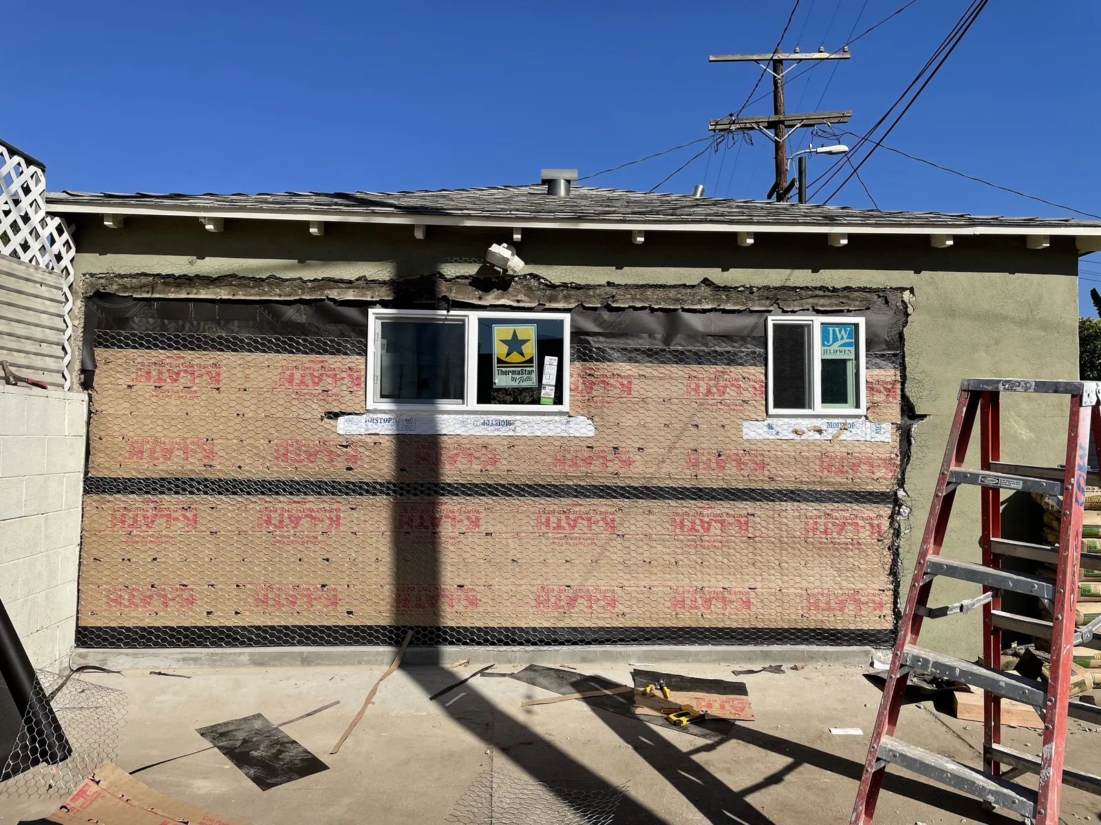 Weather-resistant paper and wire mesh installed over exterior sheathing around two windows