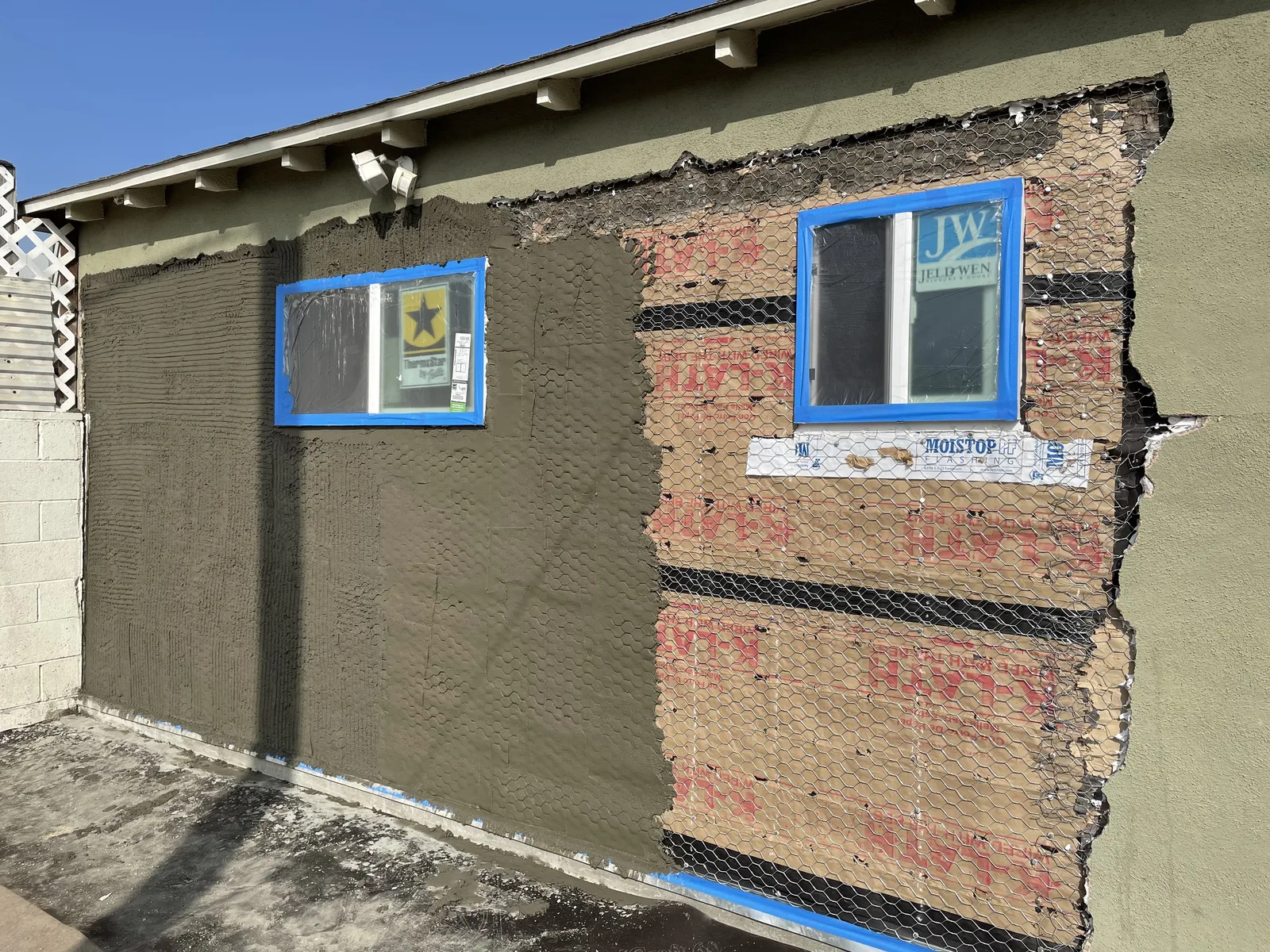 The first coat of new stucco applied over exterior sheathing around a window