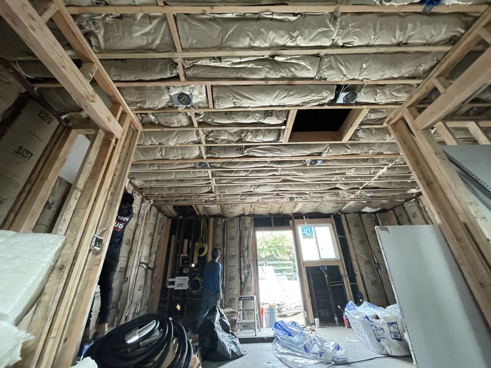 Ceiling insulation and framed door openings, with a window at the end of a hallway