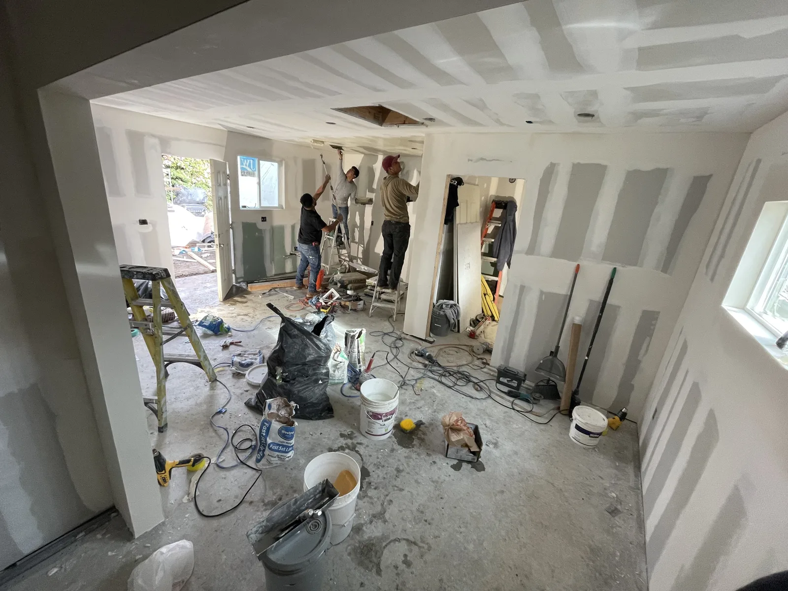 Workers finishing drywall seams in a main living area