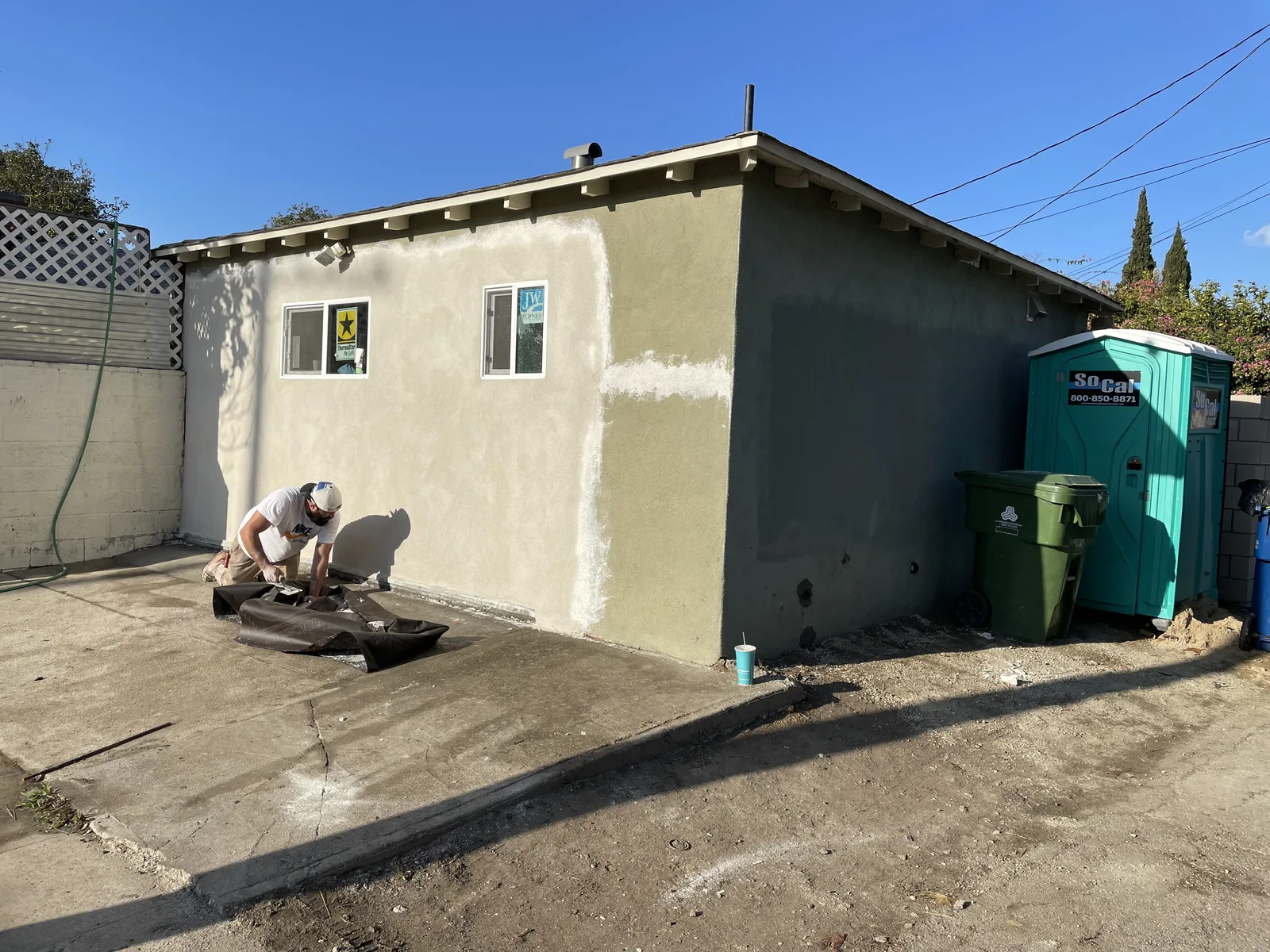 New stucco applied over an exterior wall, with new windows in place