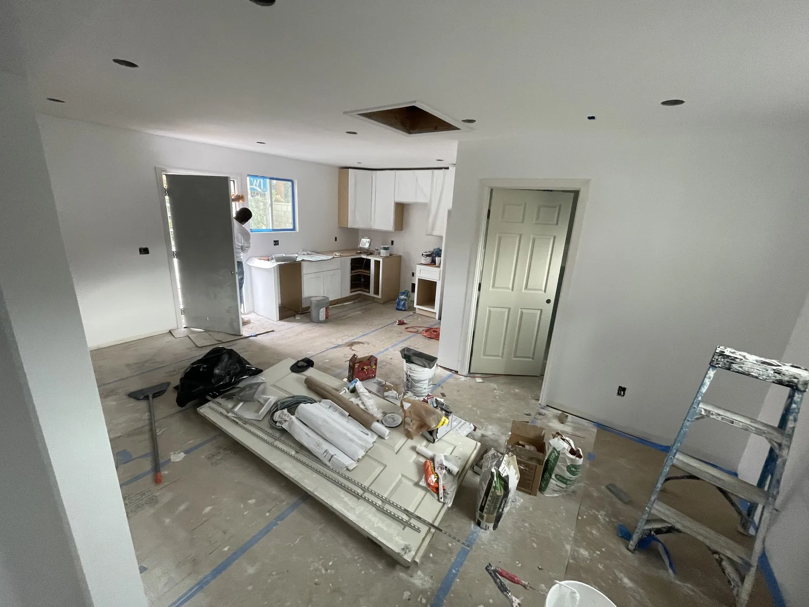 Kitchen cabinets being installed, with flooring materials staged nearby