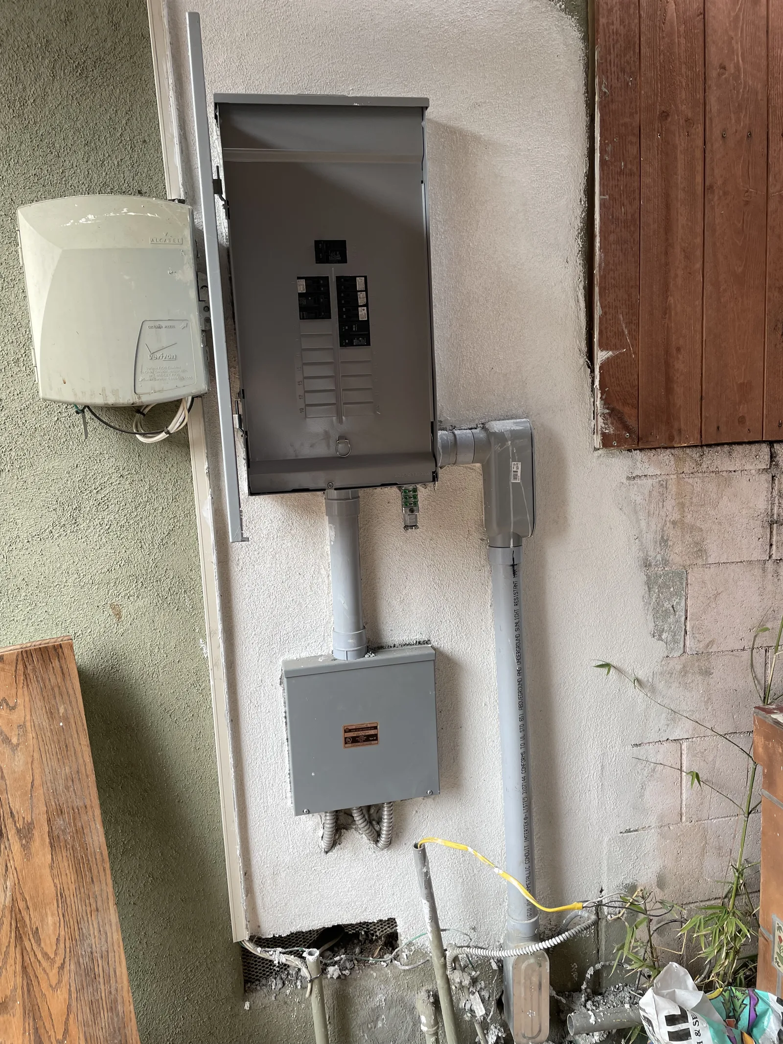 A new electrical panel and sub-panel mounted on a finished exterior wall