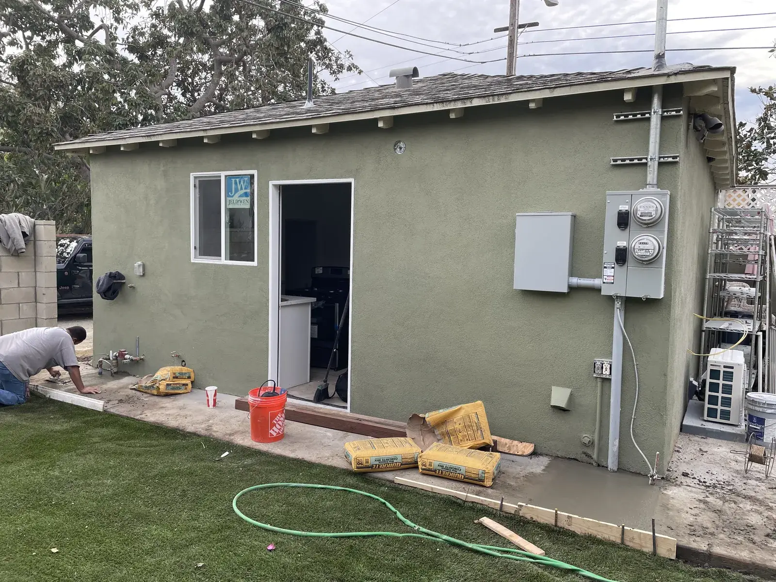A finished exterior with new stucco, electrical panels, and a concrete walkway