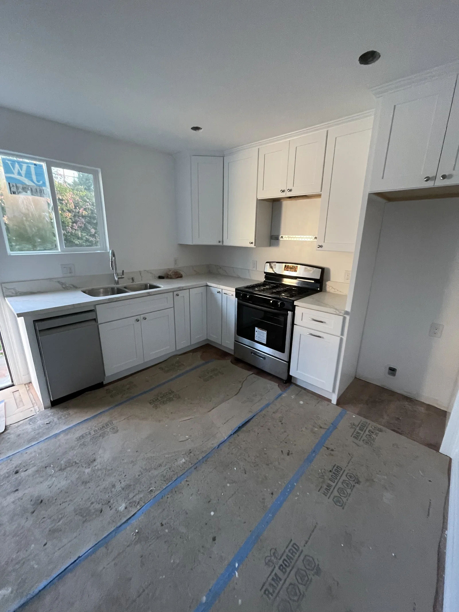 A kitchen with white cabinets, a dishwasher, and a range installed