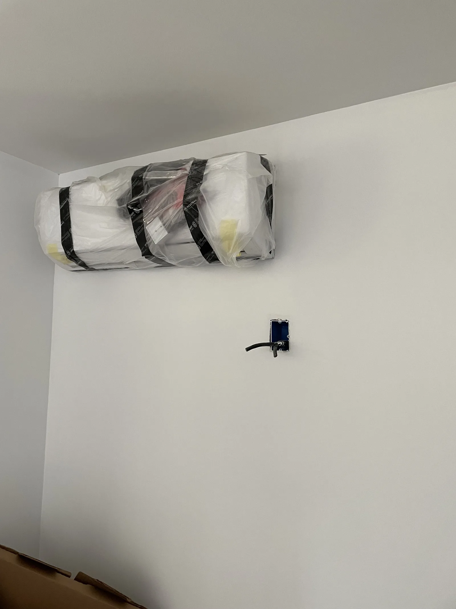 A wall-mounted mini-split air conditioning unit, still wrapped in packaging