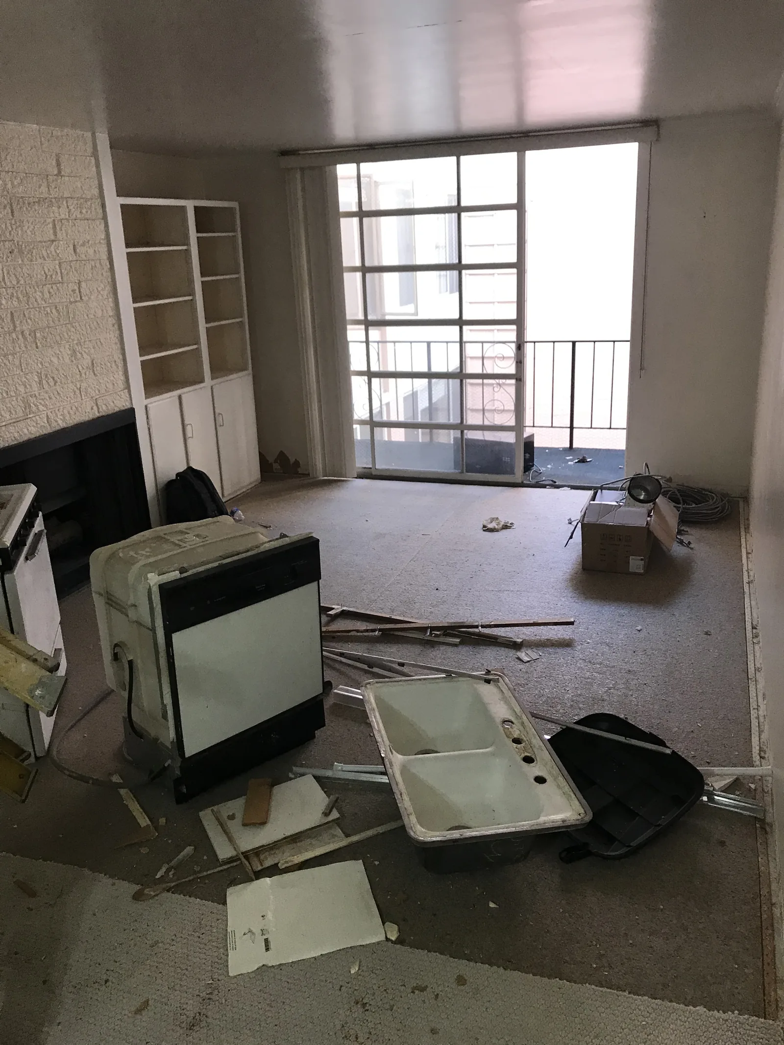 Kitchen demolition debris, including the old dishwasher, sink, and stove, staged in the living room
