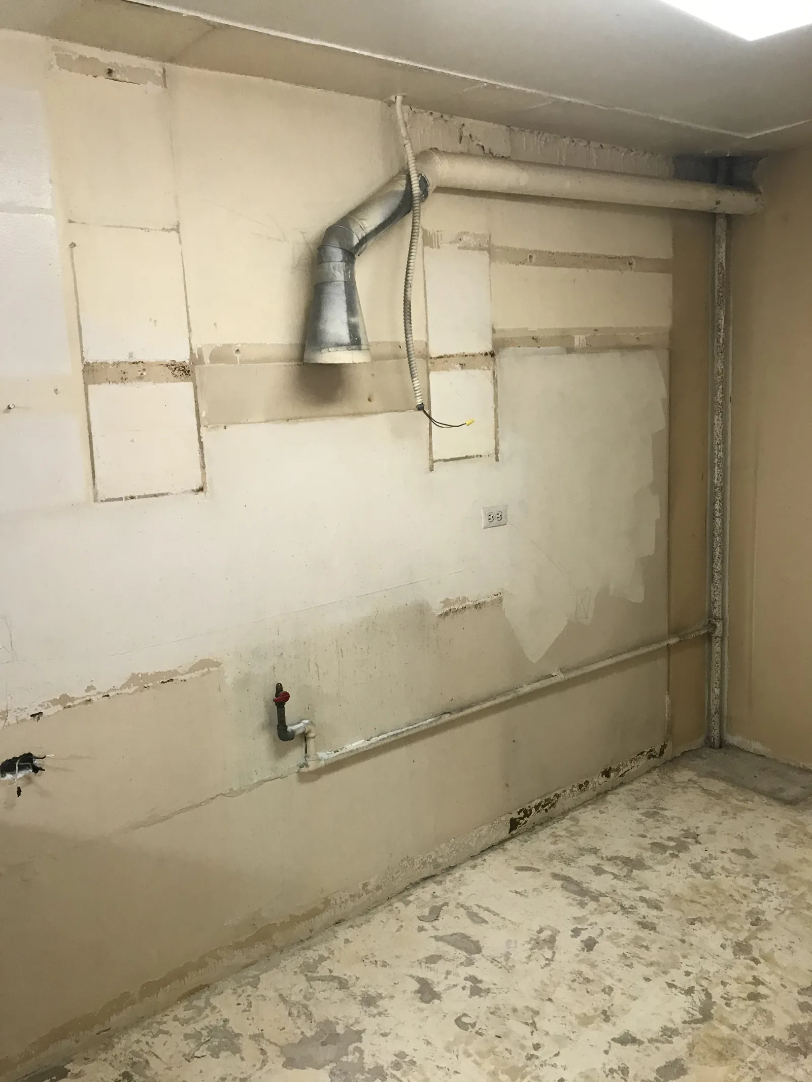 A close view of a bathroom corner with a vent duct exposed during demolition