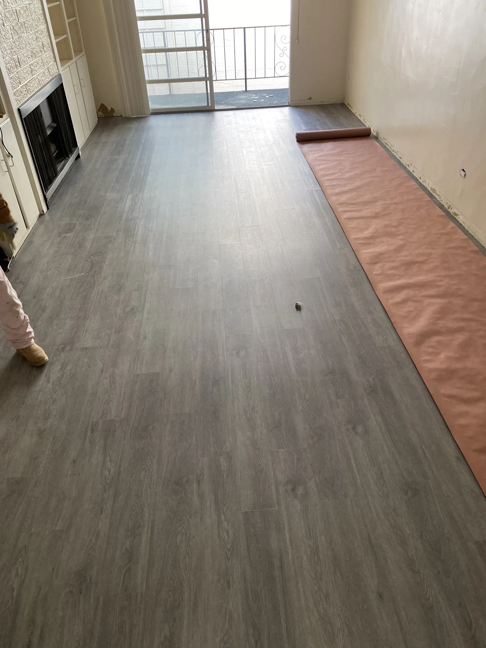 New vinyl plank flooring partially installed in a hallway with a balcony visible beyond