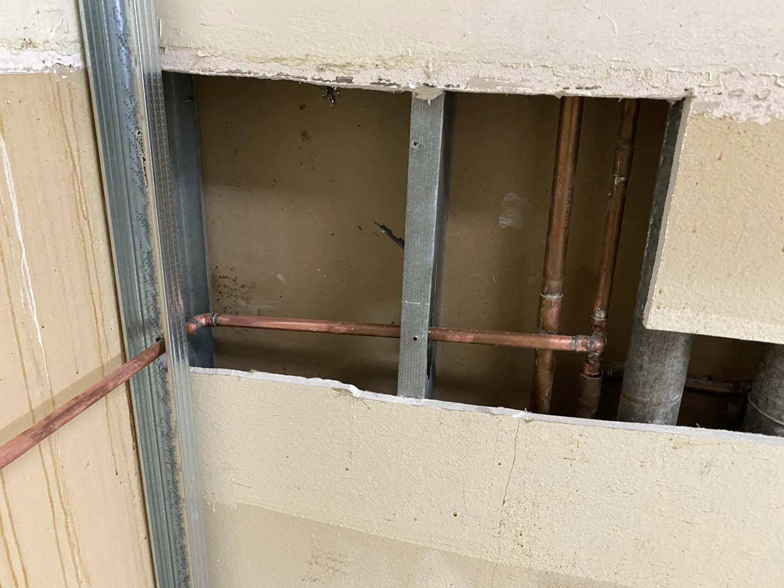 New metal stud framing in a bathroom with copper pipe stub-outs run through it