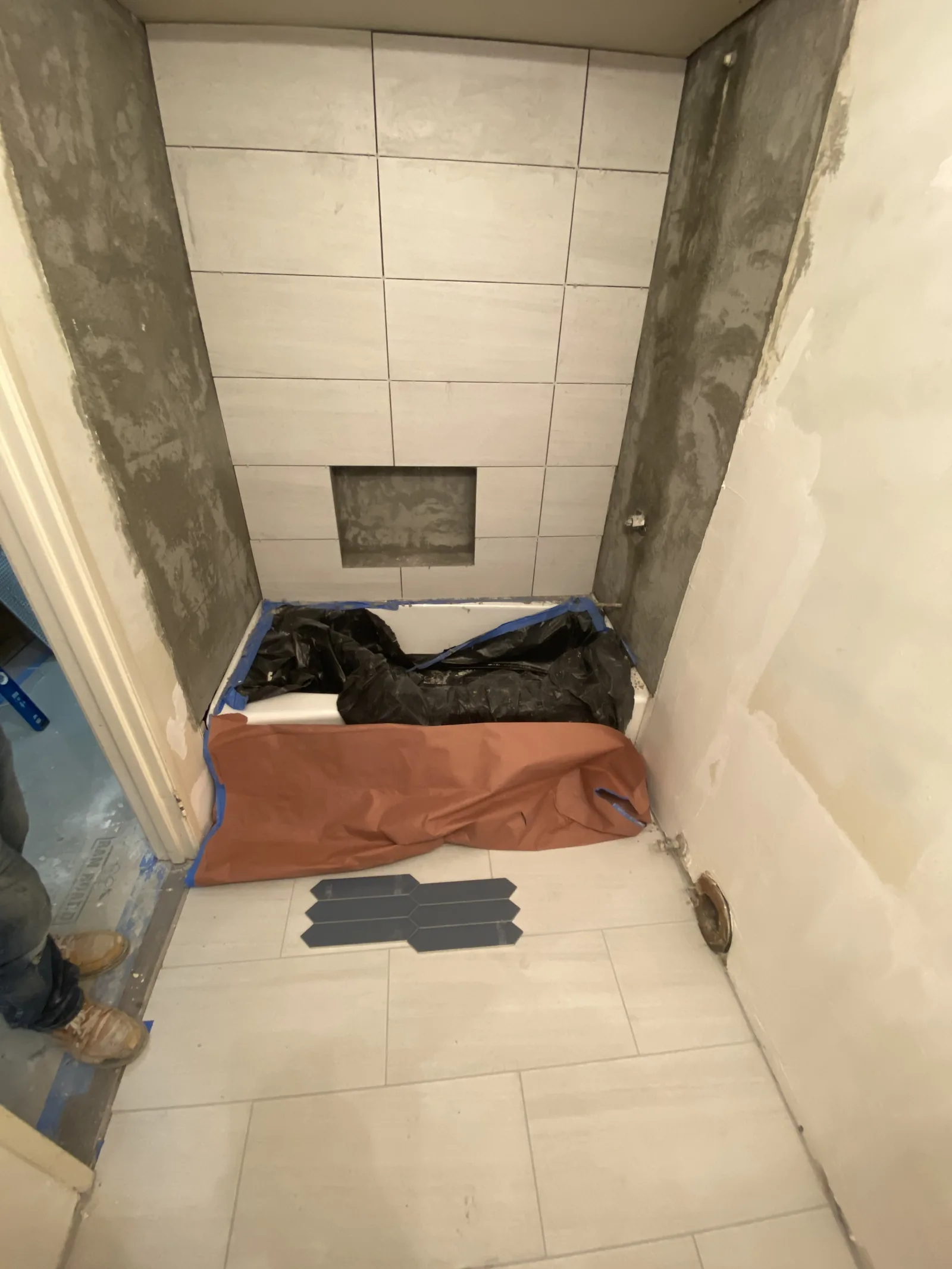 A finished tiled shower pan with the tile still covered in protective sheeting