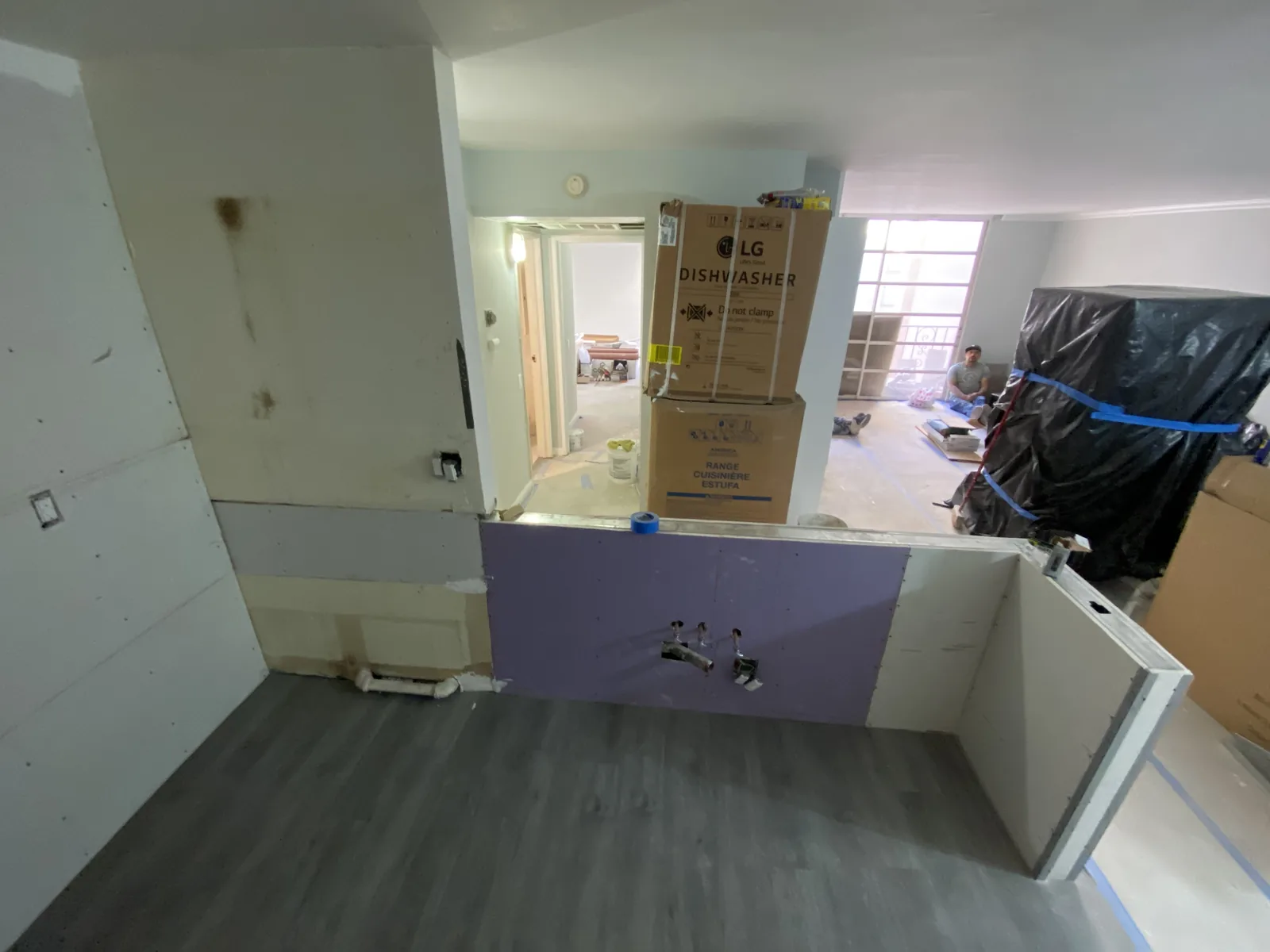 A room with new moisture-resistant drywall installed and new flooring partially laid