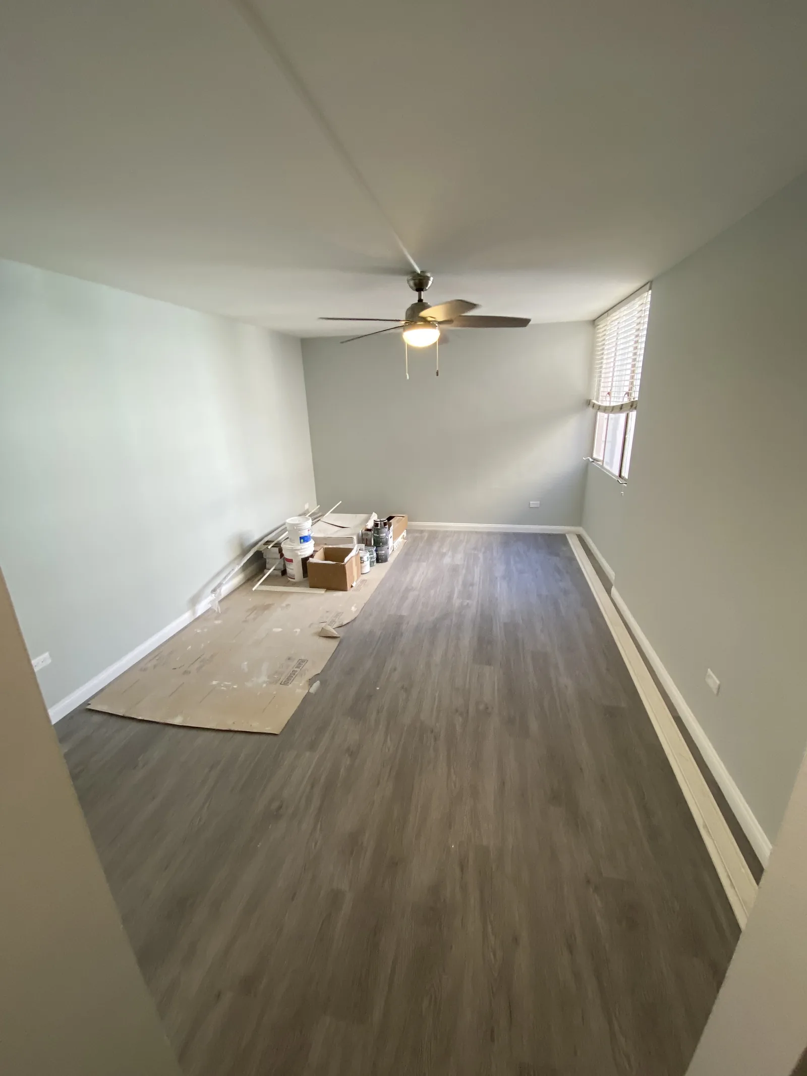 An empty room with new flooring installed and construction materials still on the floor
