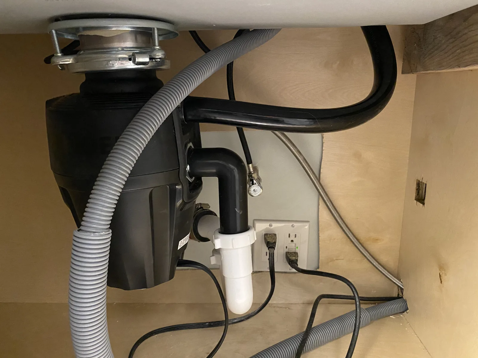 A new garbage disposal installed under the kitchen sink with the dishwasher drain line and outlet wired in