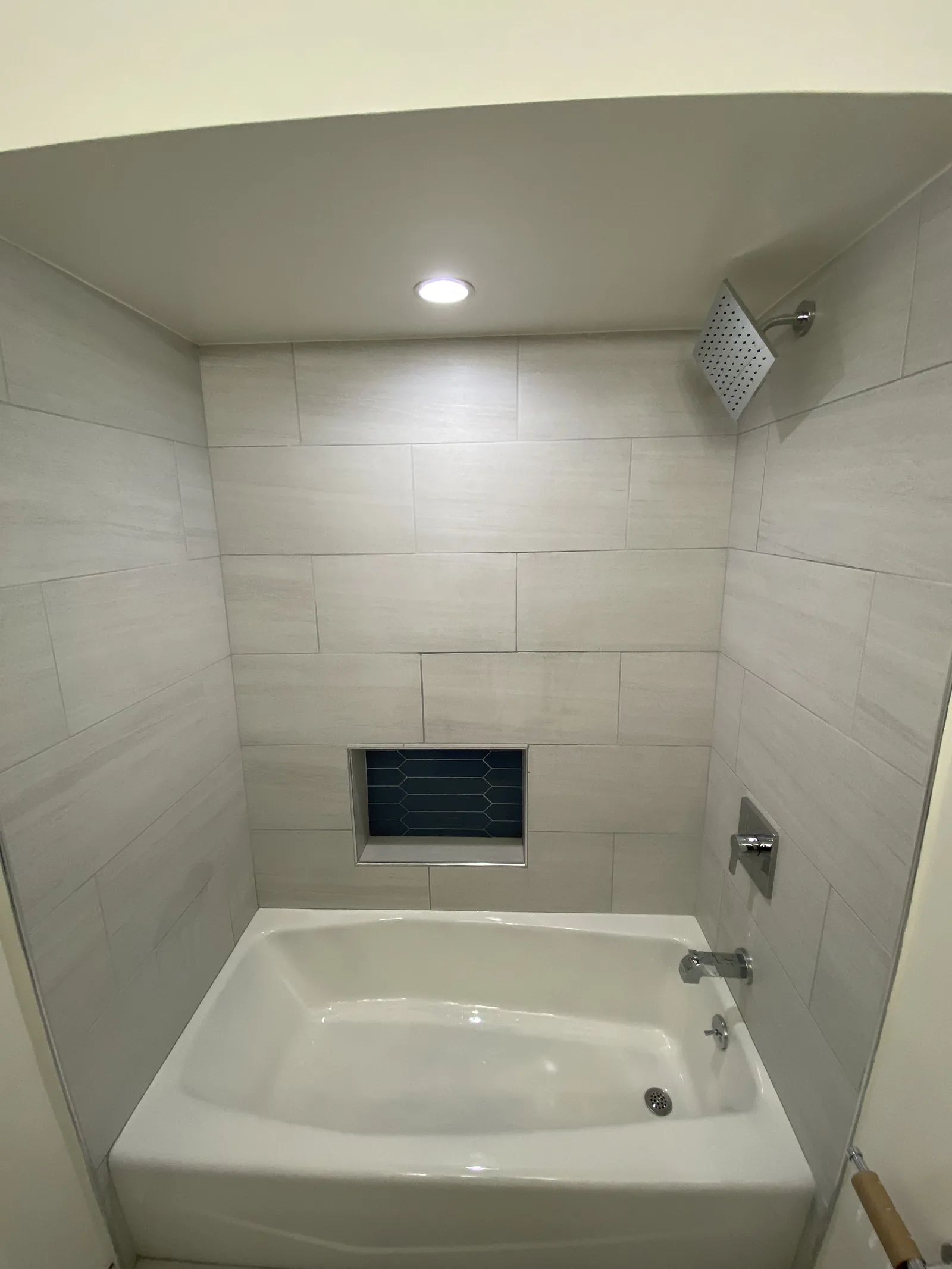 A close view of the finished tub surround tile and shower fixtures in the first bathroom