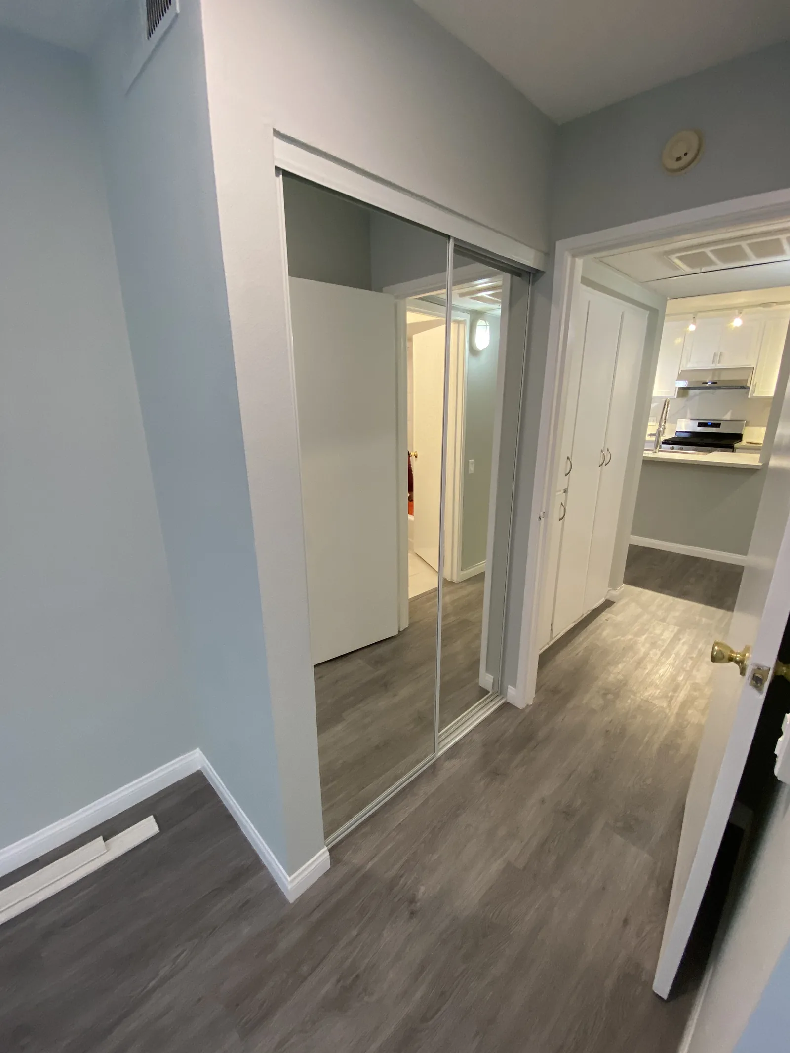 A hallway with the mirrored closet doors and new flooring